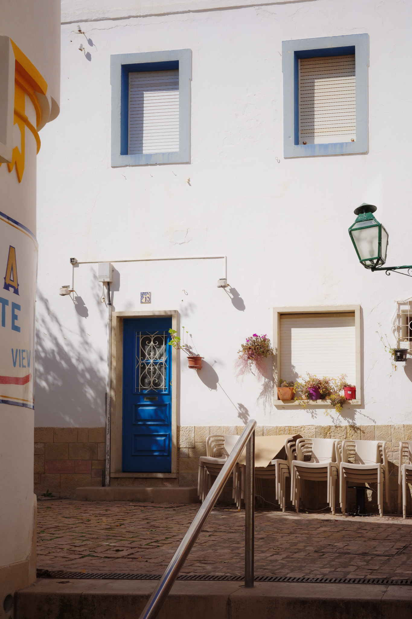 Kleine schattige Straßen mit auffälliger blauer Tür im sonnigen Albufeira, Portugal. Von Connor Redmond.