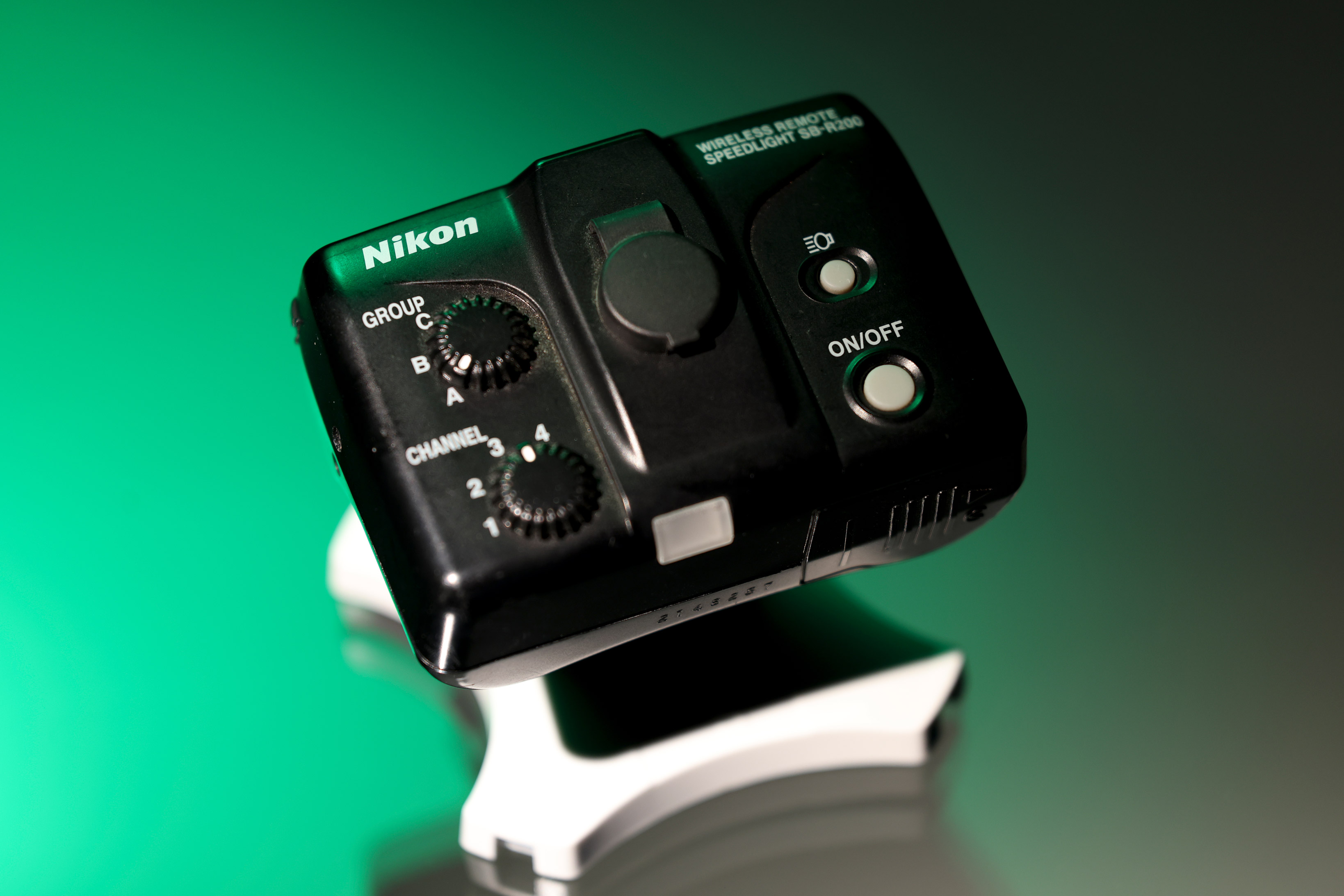 Nikon SB-R200 Speedlight against a mint green background.