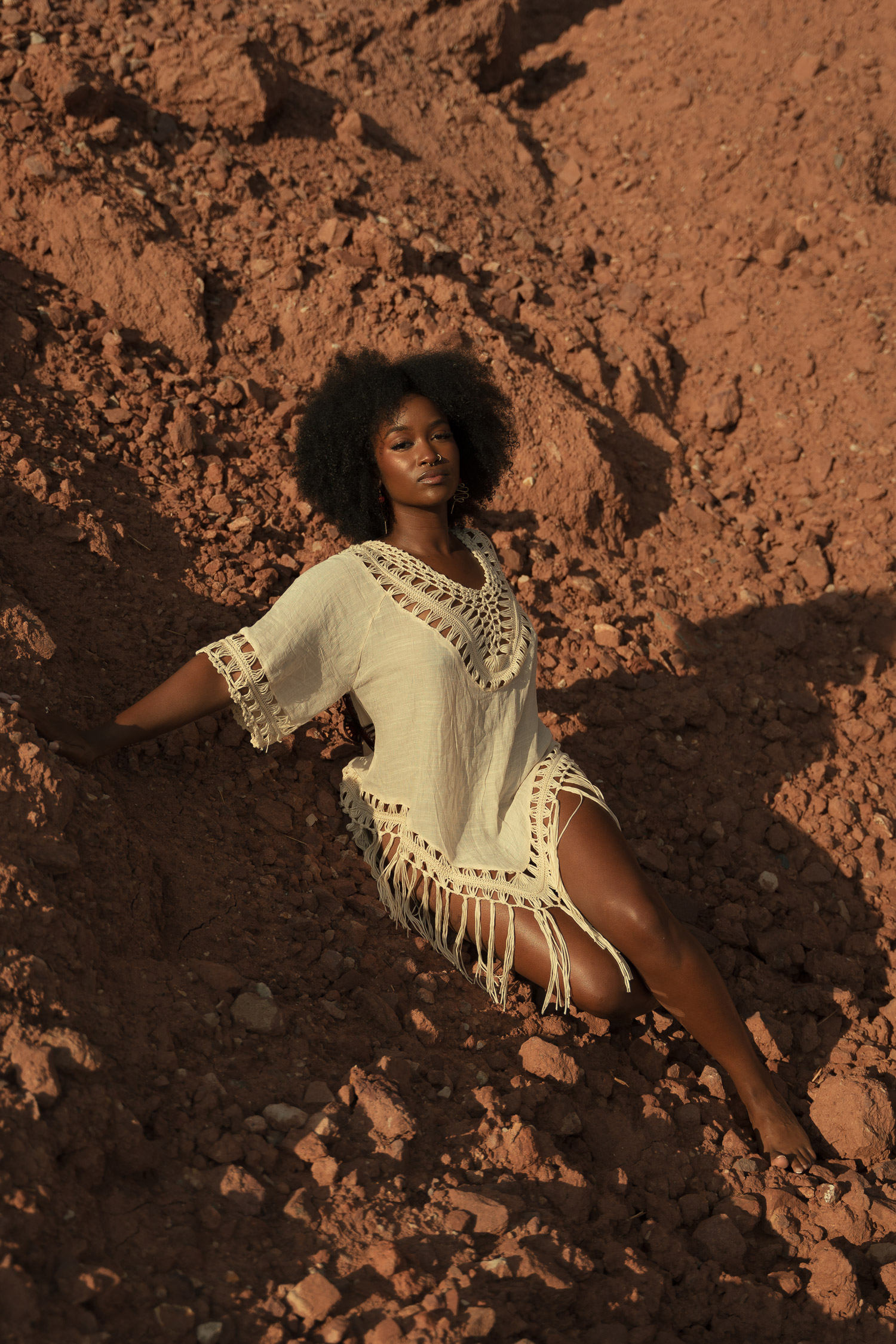 Portrait of black woman on top of brown rocks in a white shirt