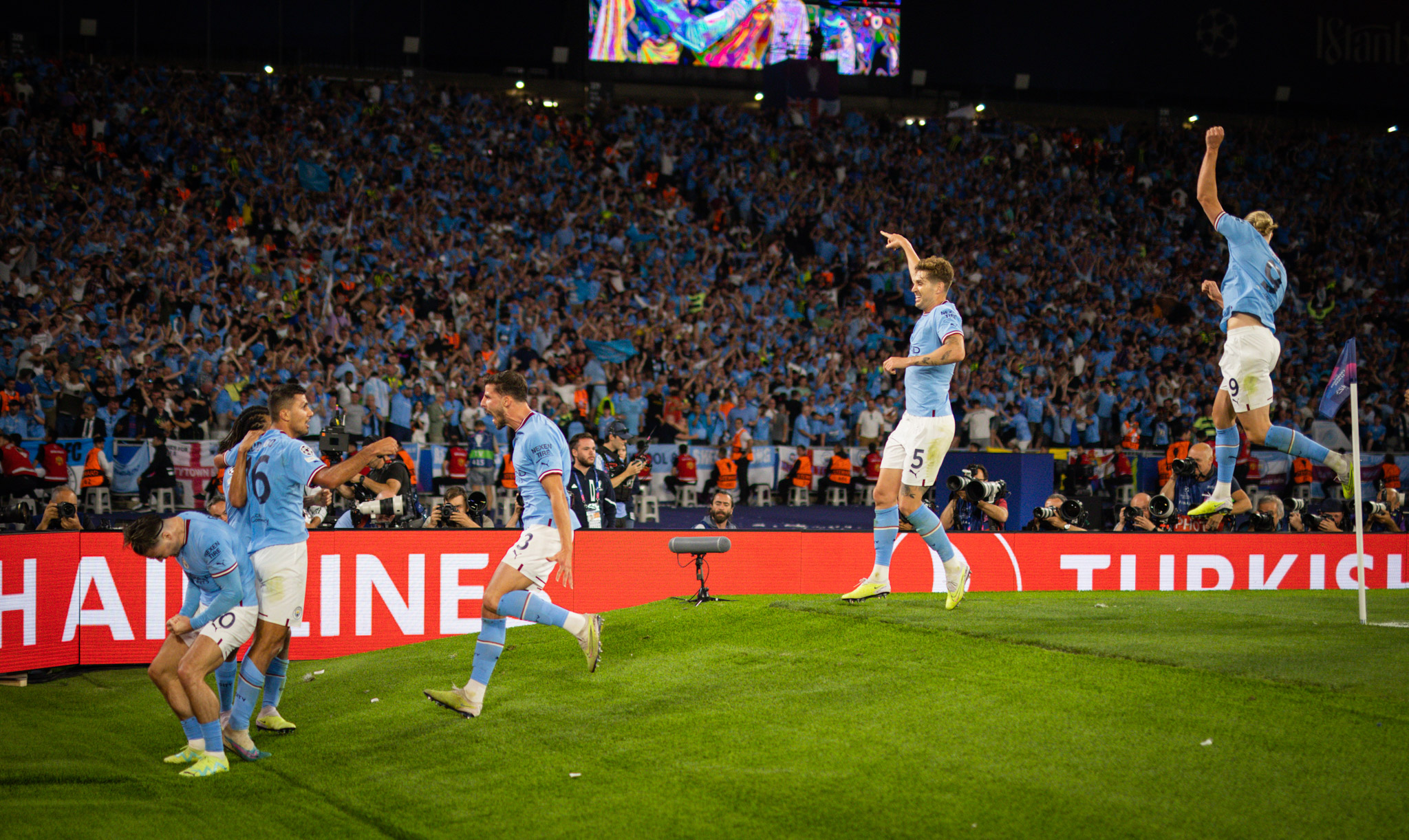 Six Manchester City players, including Erling Haaland, celebrate a goal at the corner of the pitch. By Moritz Muller.
