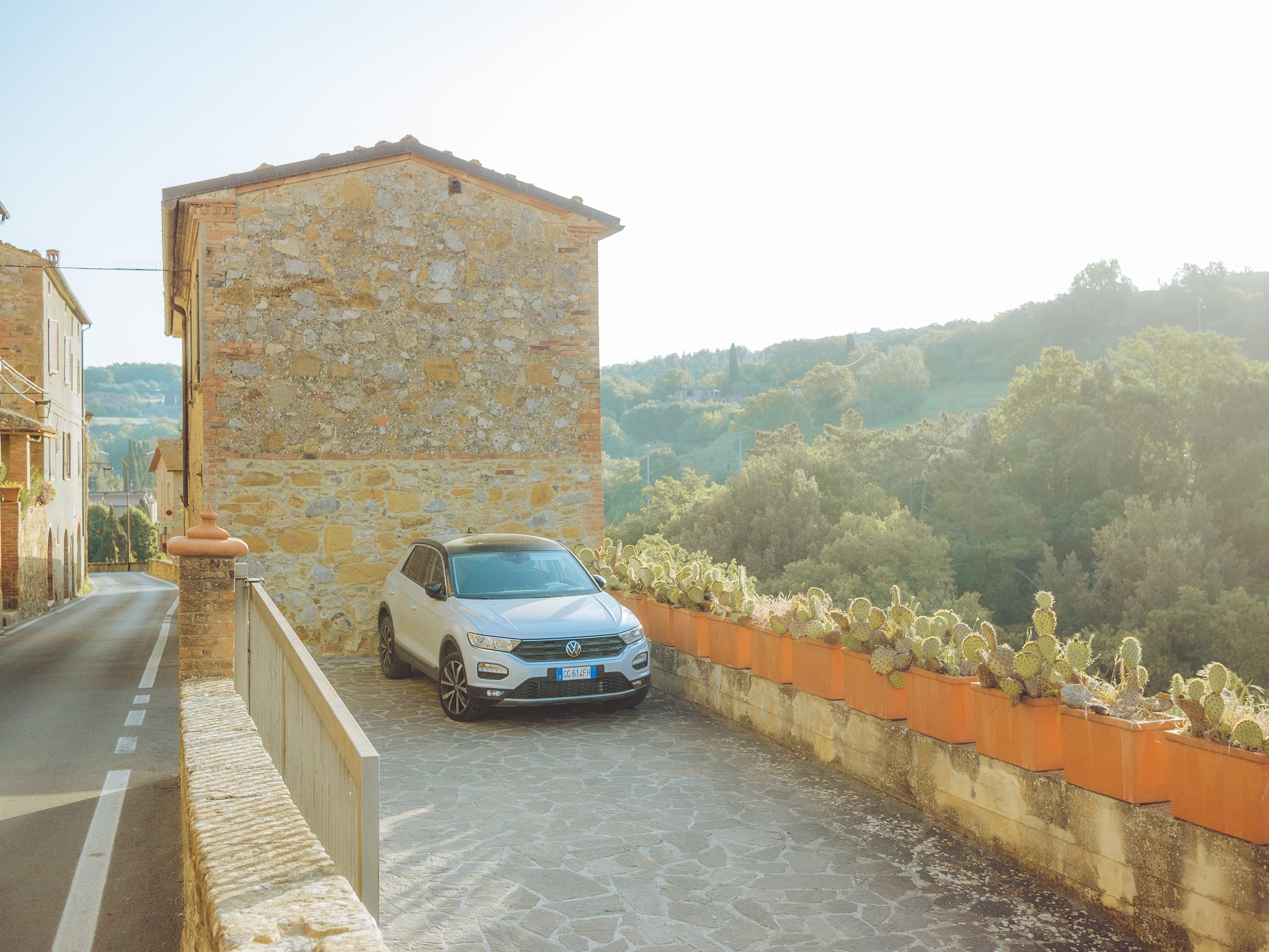 A white car parked outside a building in Petrolo, Tuscany. There are trees and hills in the background.
