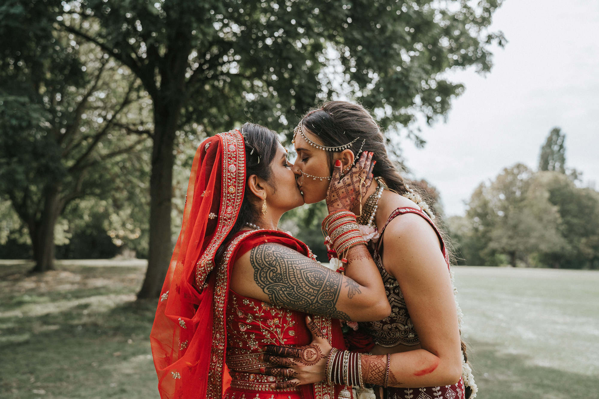 
Newlyweds kissing on their wedding day. Both are dressed in red Indian wedding gowns. Taken by Steph Large on a Sony A7 III

