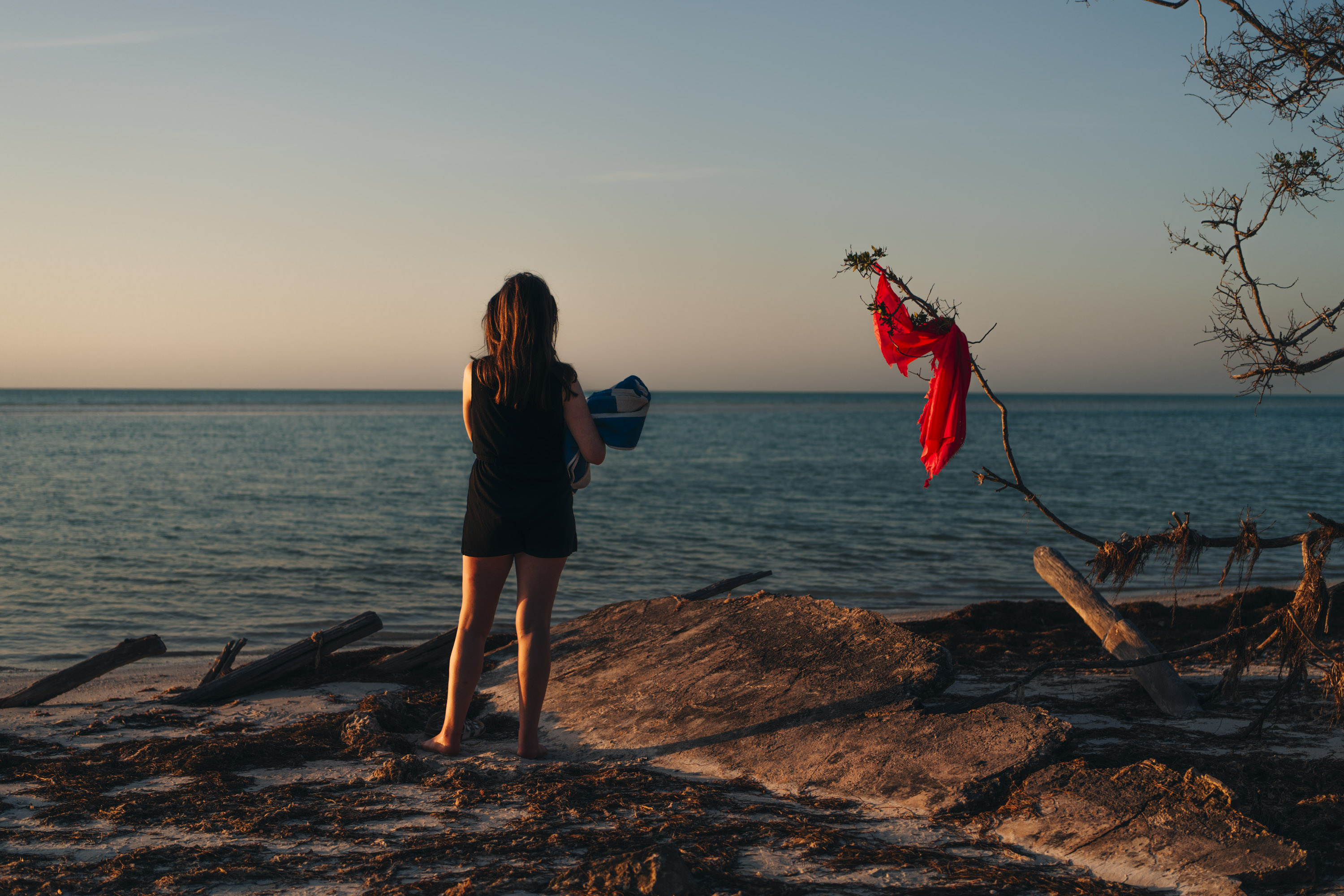 Een persoon kijkt uit over de zee terwijl hij op het strand in Mexico bij zonsondergang ligt. Gefotografeerd door Ian Howorth.