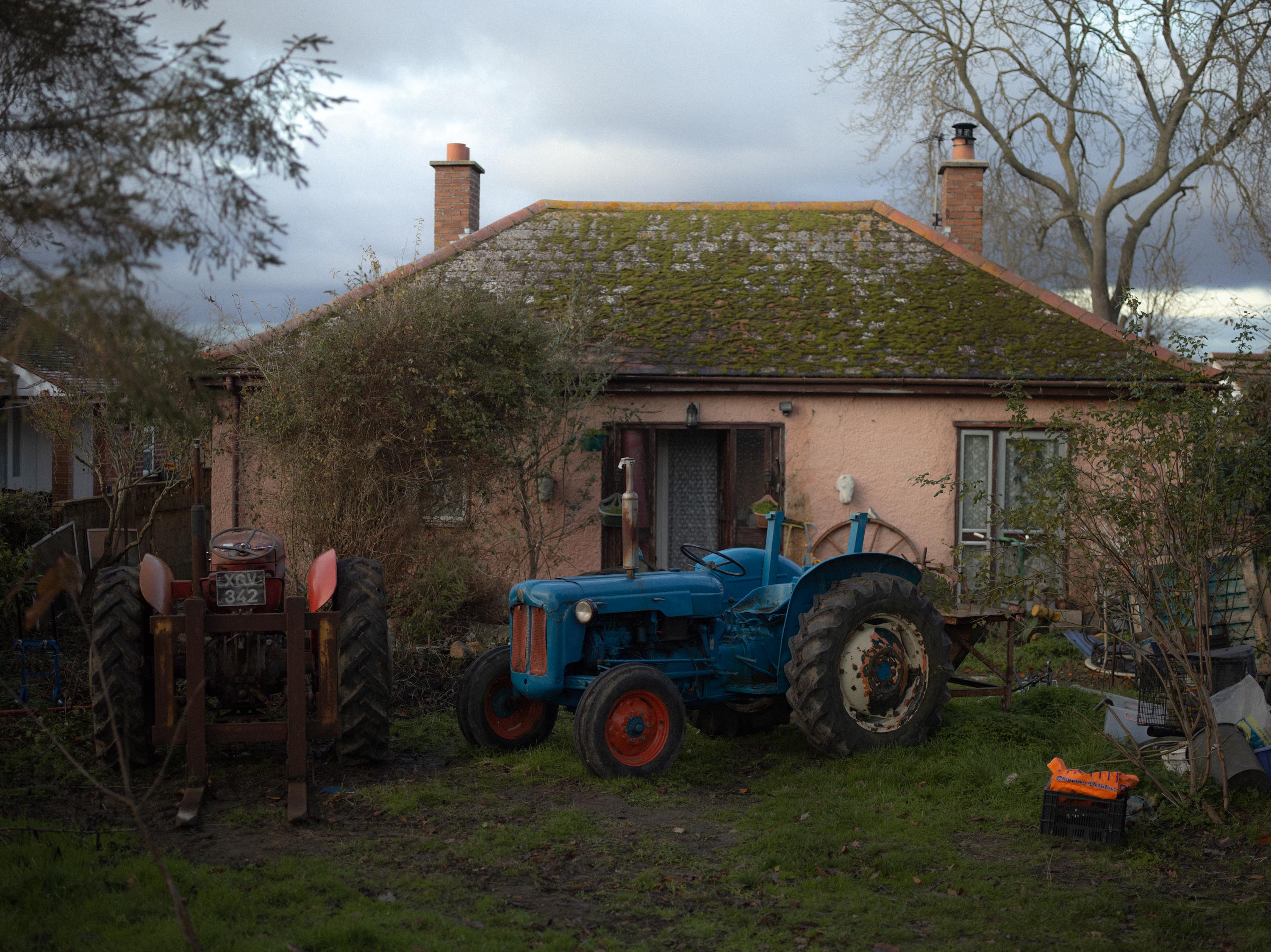 A photo of pink house and a tractor parked on the front yard, shot on Phase One P45 Plus by Ian Howorth