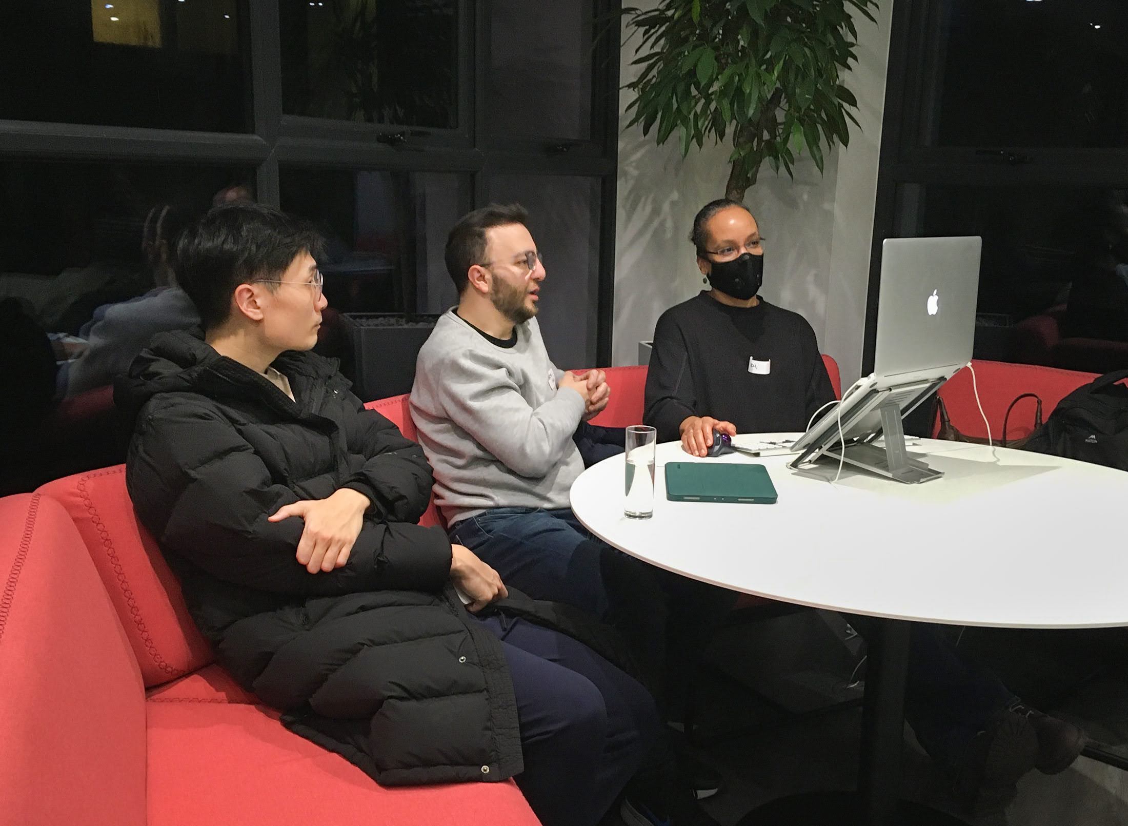 Three people sitting on a sofa looking at a computer while attending an MPB and codebar event Brighton. 