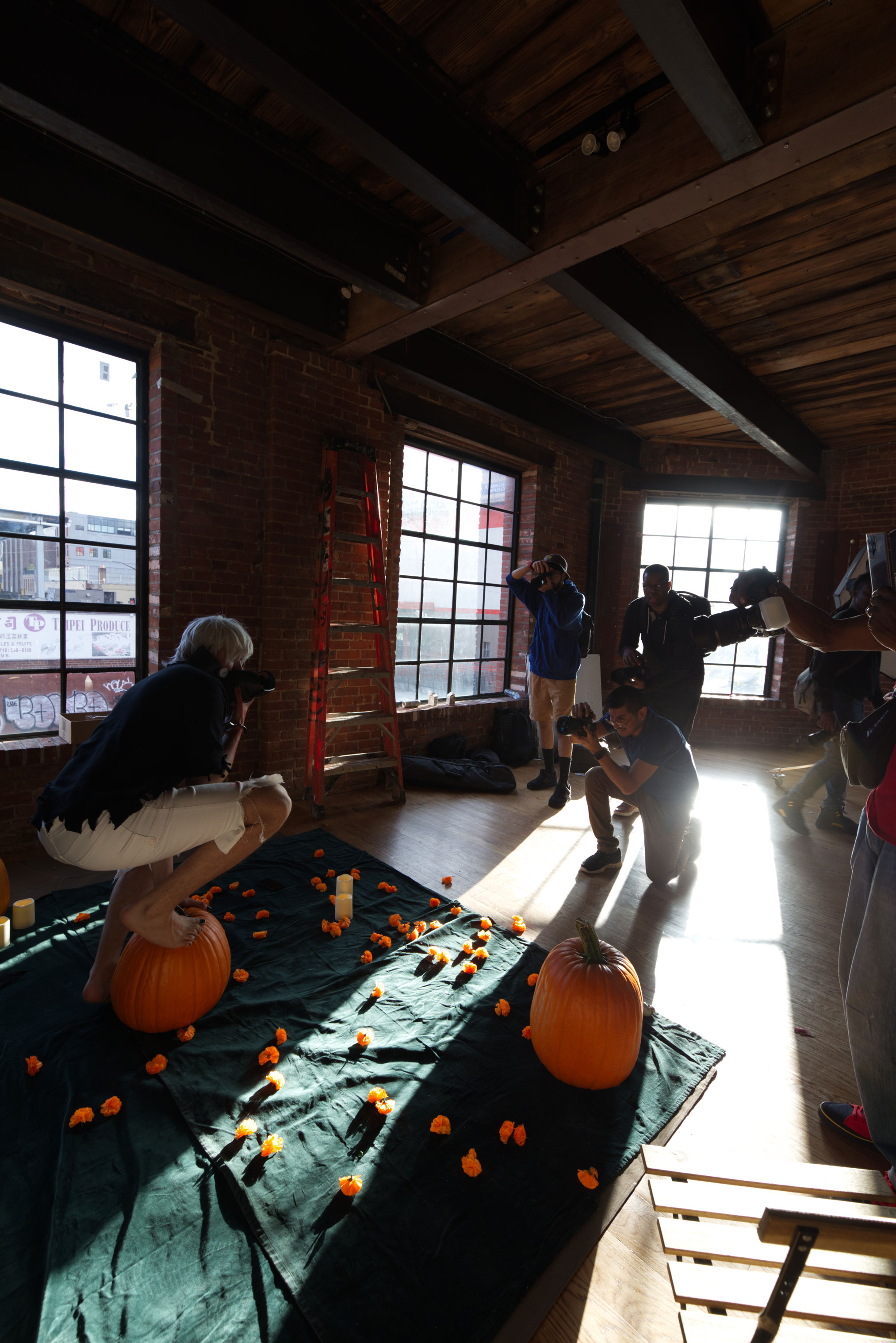 Group of photographers shooting a cosplayer around a fall-themed set.

