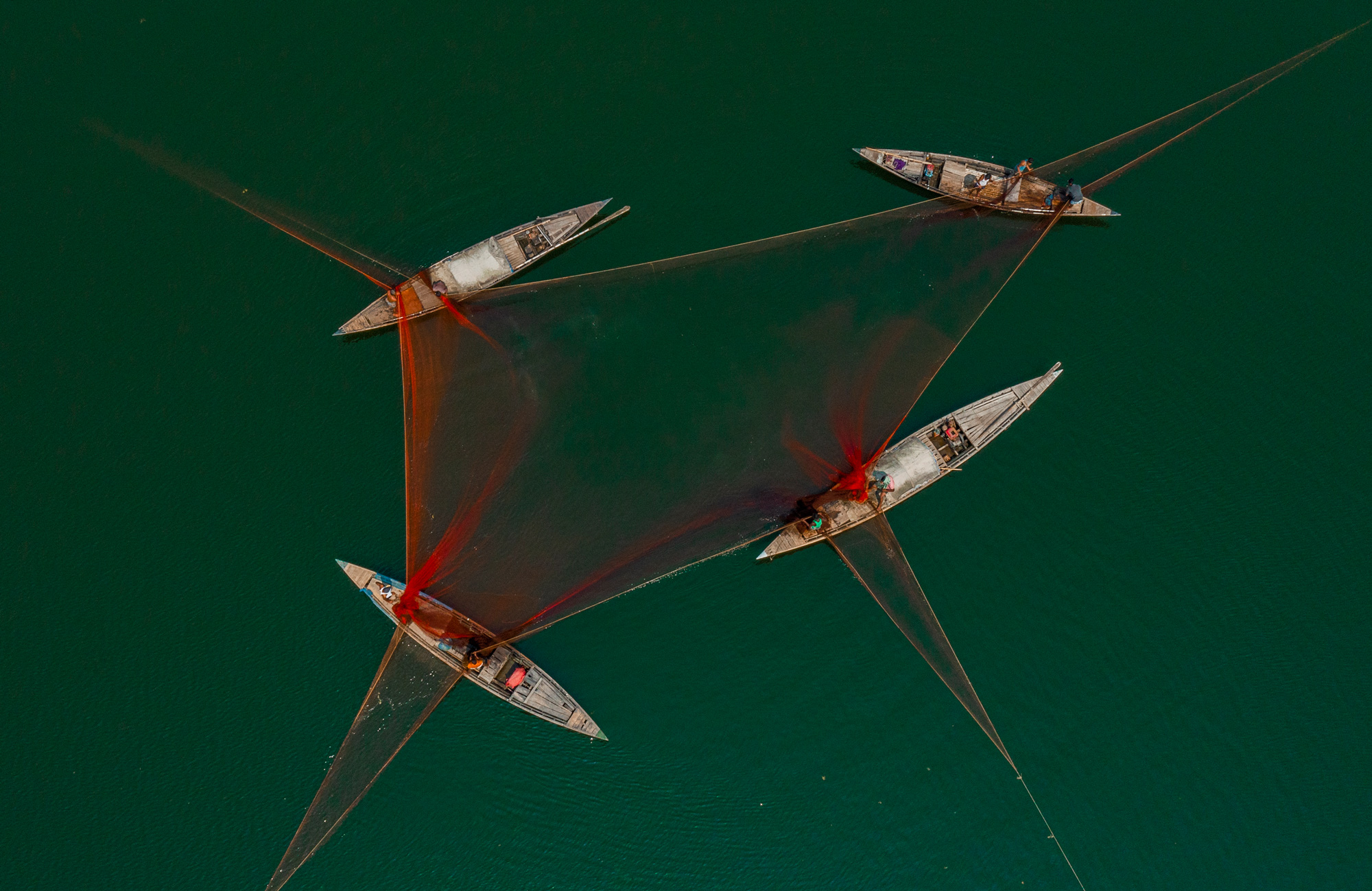 A birds-eye view of four fishing boats connected with netting, photo by MD Ashraful-Islam

