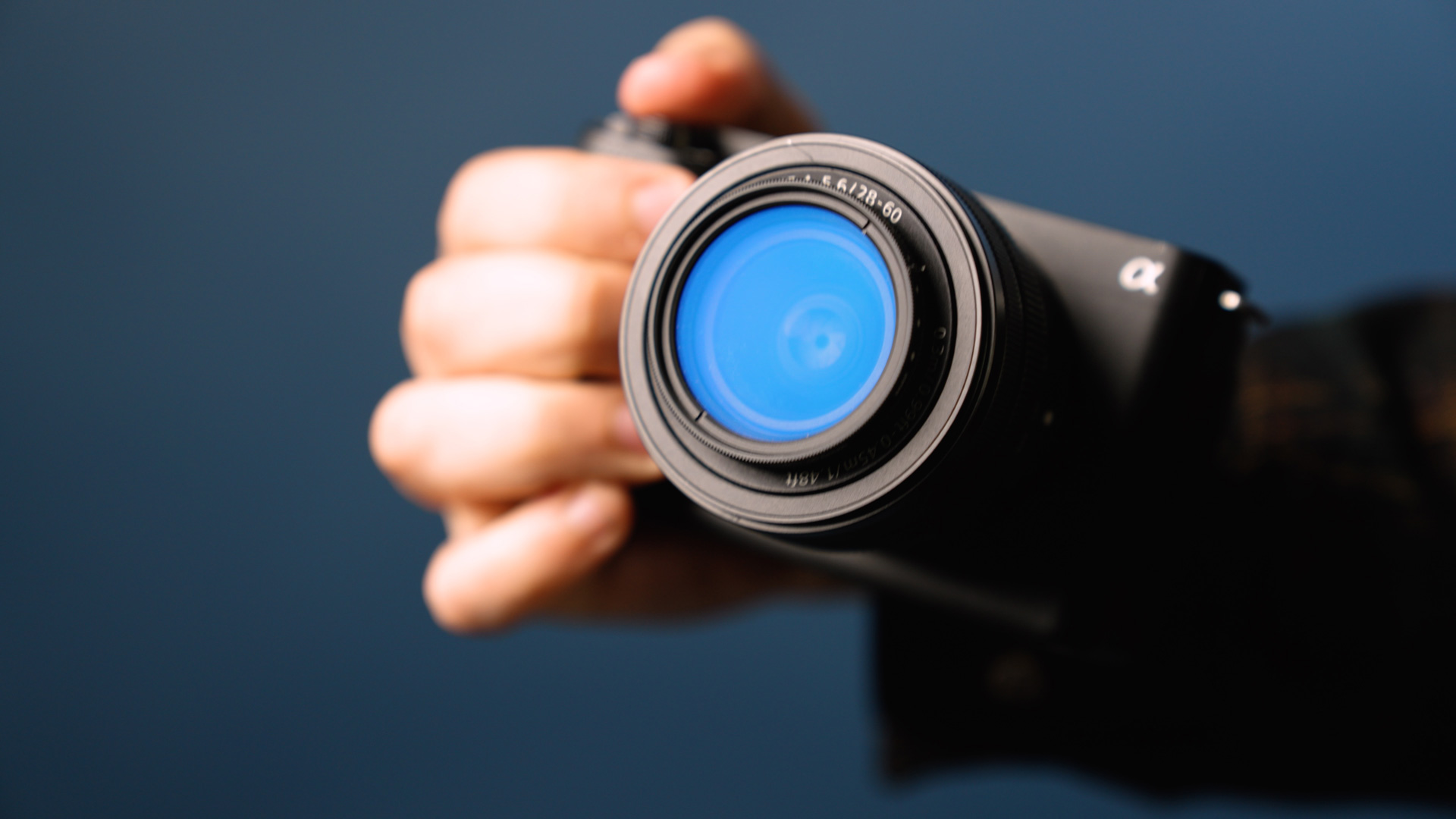 Une main tient la Sony ZV-E1 sur un fond bleu