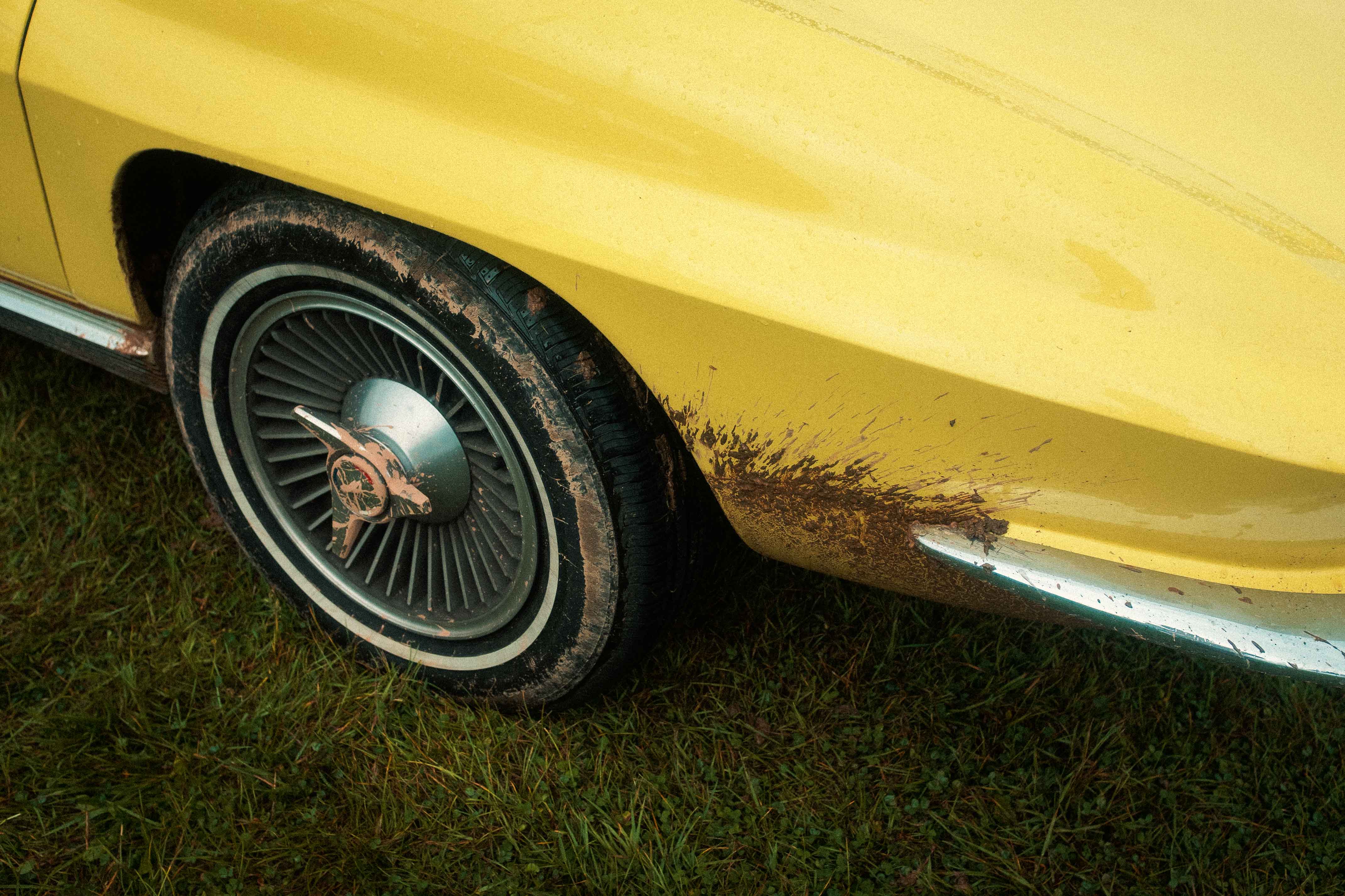 An image of a yellow vintage car wheel covered in dirt. Taken by Connor Redmond on the Fujifilm X100F.
