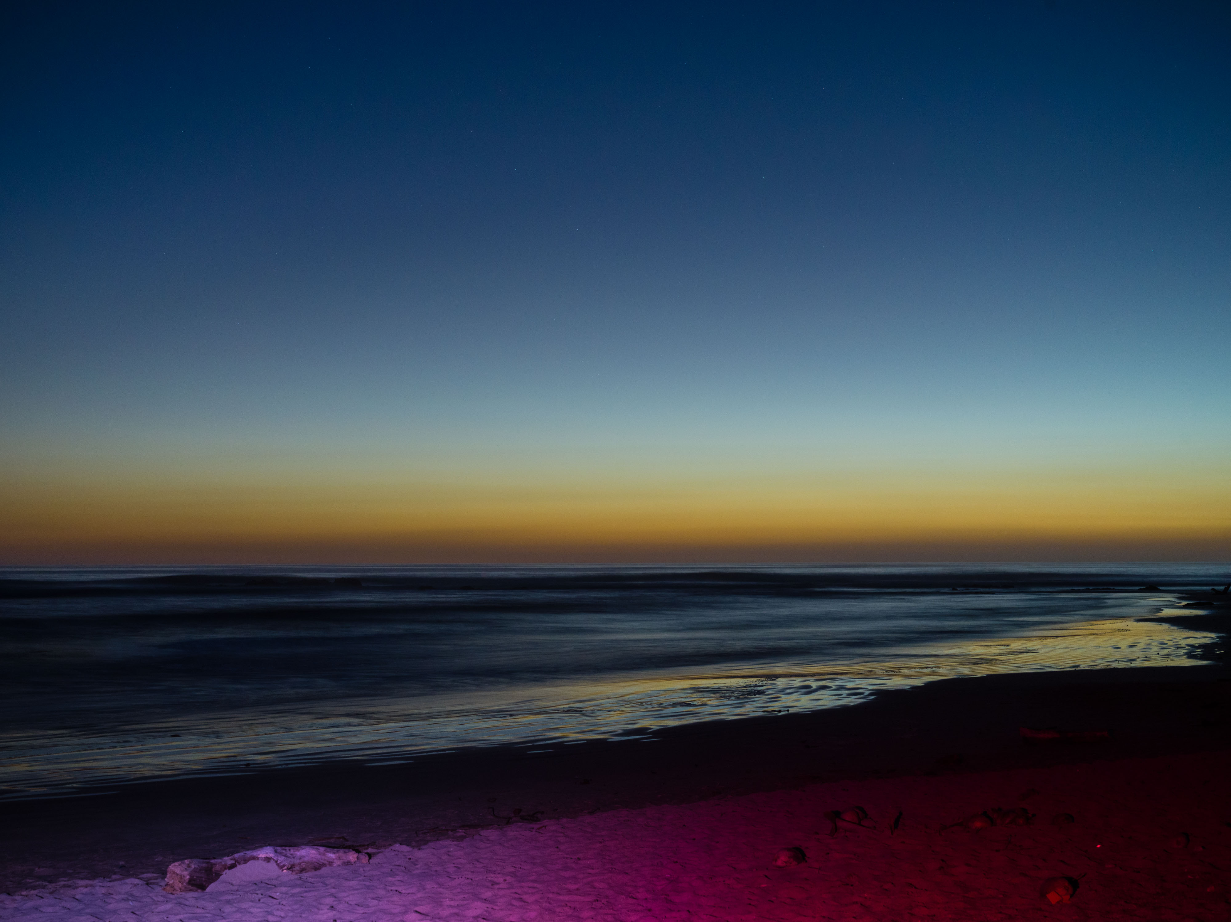 Foto van een zonsondergang op het strand met gebruik van een flitser om paars licht op het zand te maken, gefotografeerd door Ian Howorth met een Hasselblad X1D II middenformaat camera.