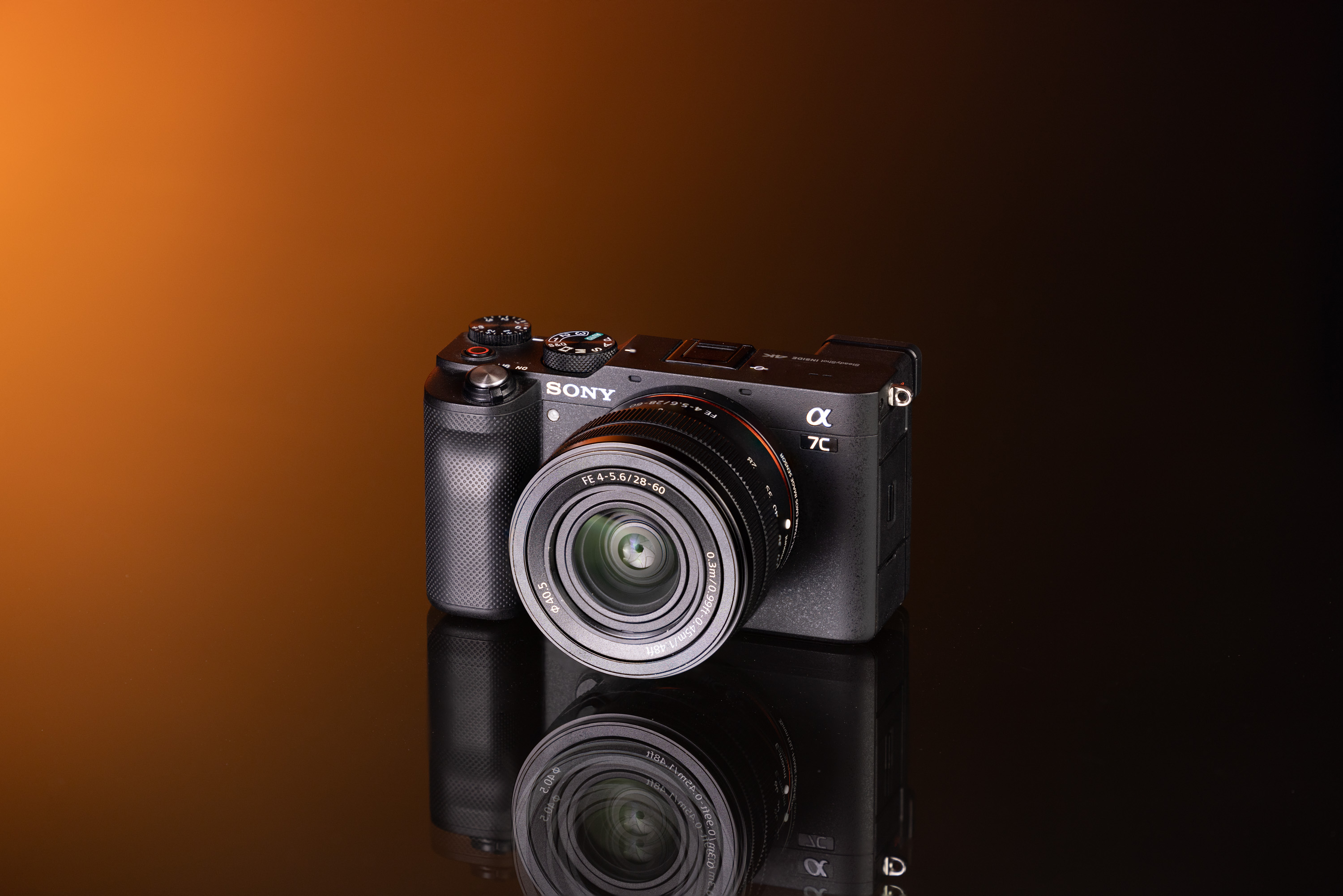 Tweedehands Sony A7C en Sony FE 28-60mm f/4-5.6 op een oranje en zwarte achtergrond