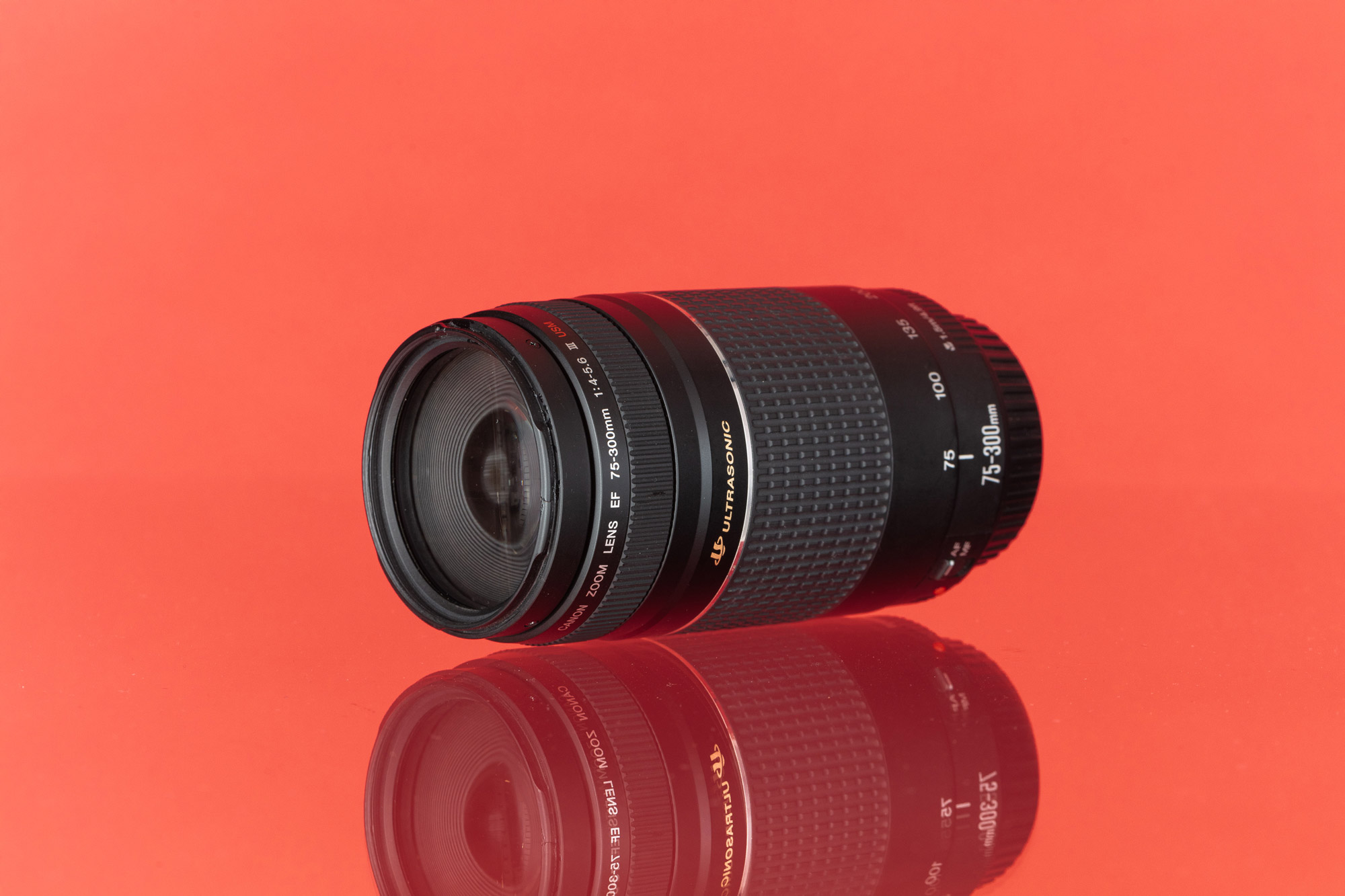 A Canon EF 75-300mm f/4-5.6 III USM tegen een rode achtergrond