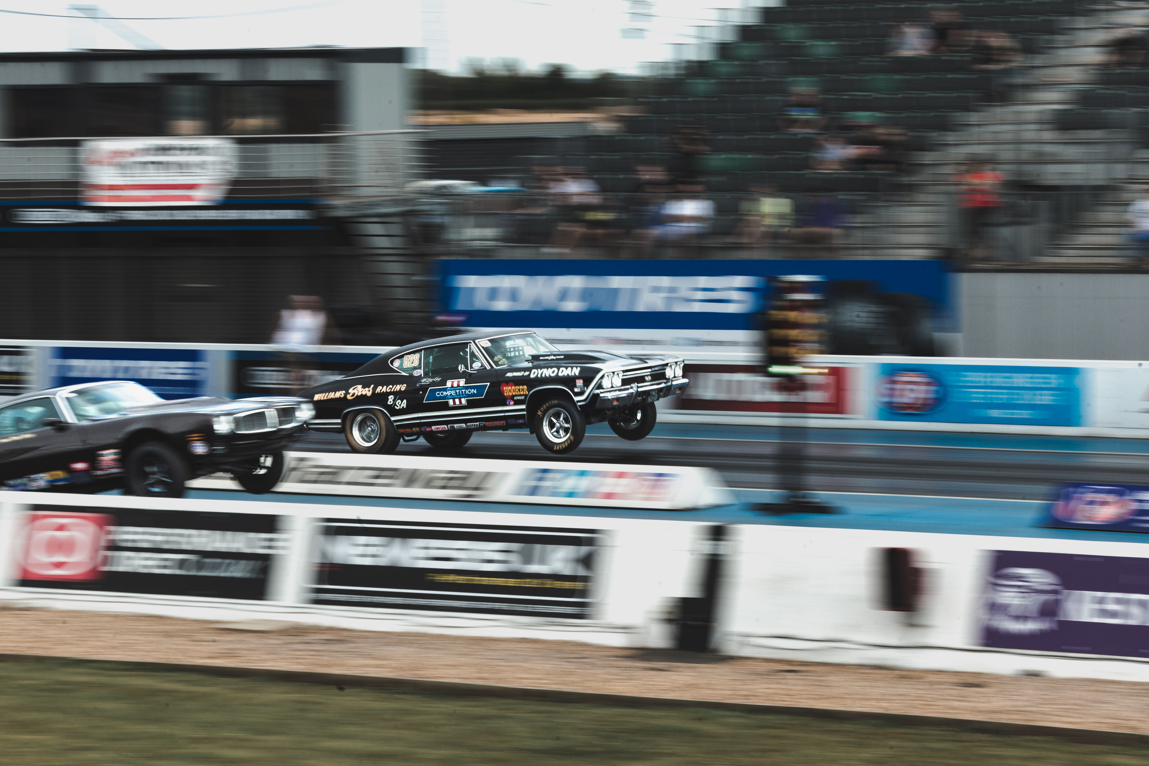 Two muscle cars jumping in the air while racing