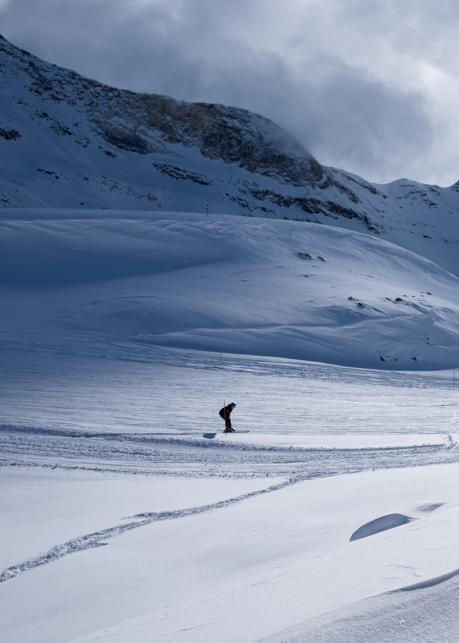 A singular skier down a slope in the Alps with mountains in the background. Taken on the Fujifilm X100VI by Amy Moore.