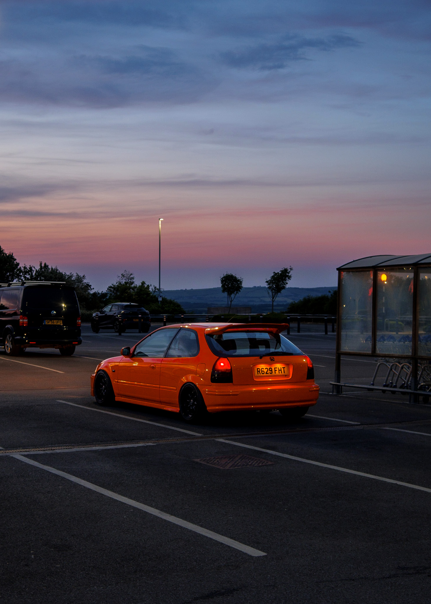 An orange car in a car park in Cornwall at sunset. By Connor Redmond. 