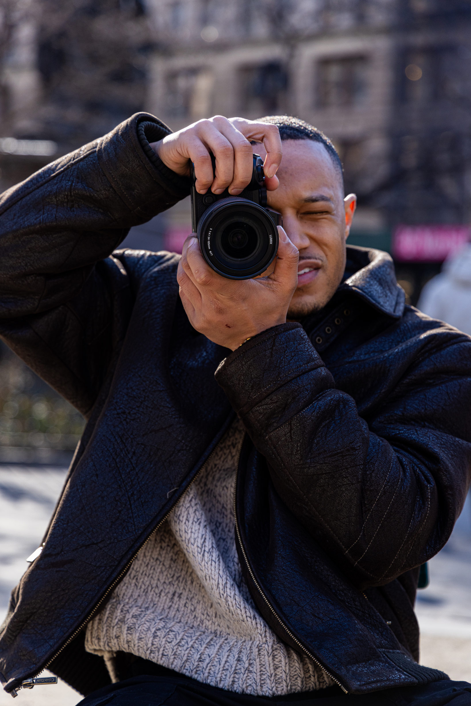 Personne en veste et pull prenant une photo tout en regardant l'appareil photo