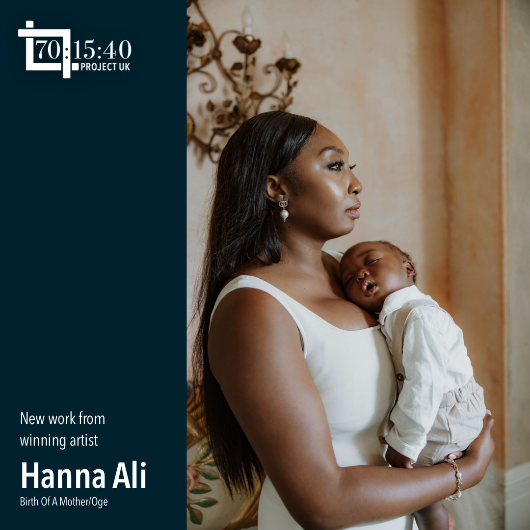 A model looks into the distance while wearing a white dress and holding a baby, photo by Hanna Ali