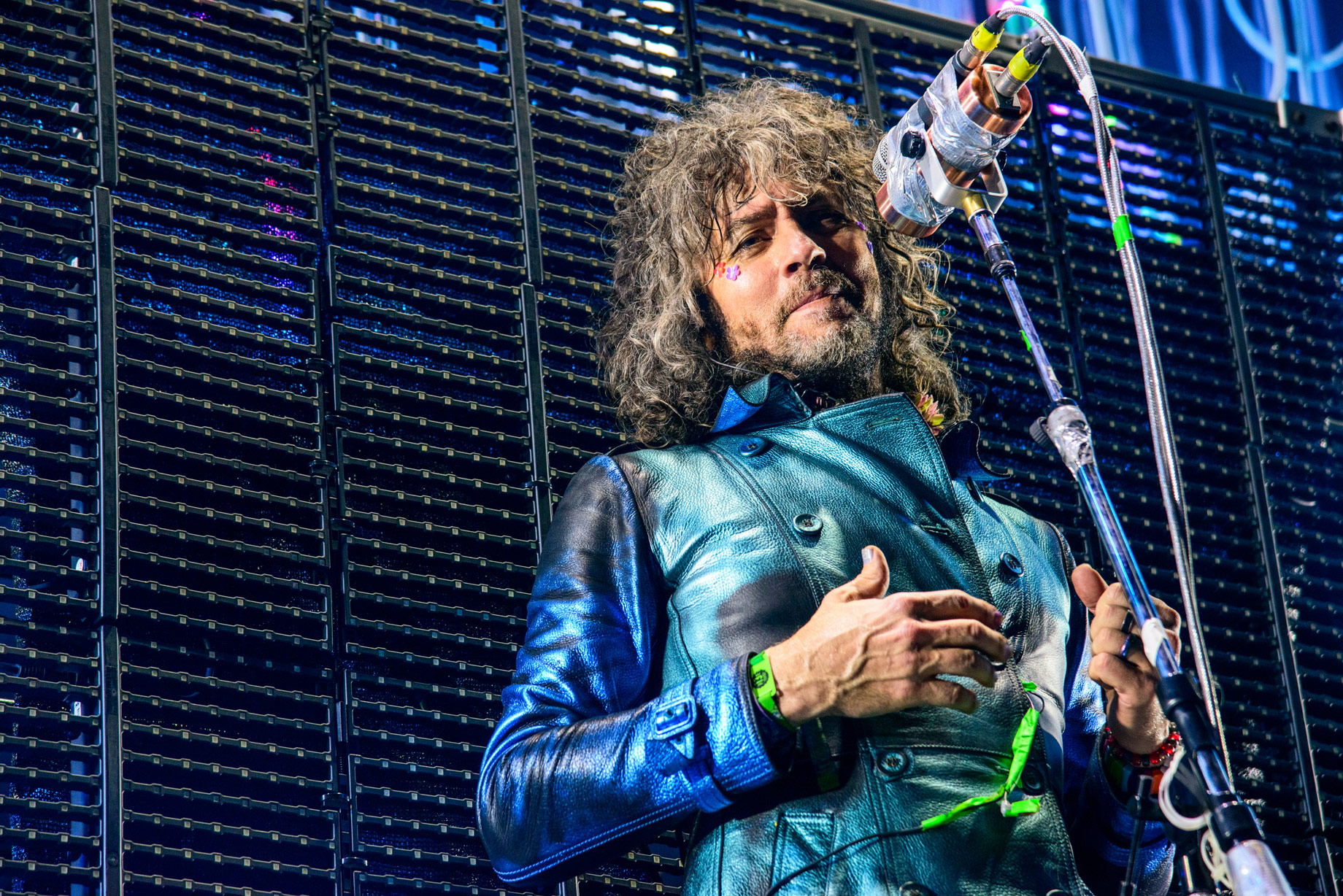 Wayne Coyne of The Flaming Lips with leather jacket and microphones looking into camera. Photo taken by James Joiner on a Nikon D800.