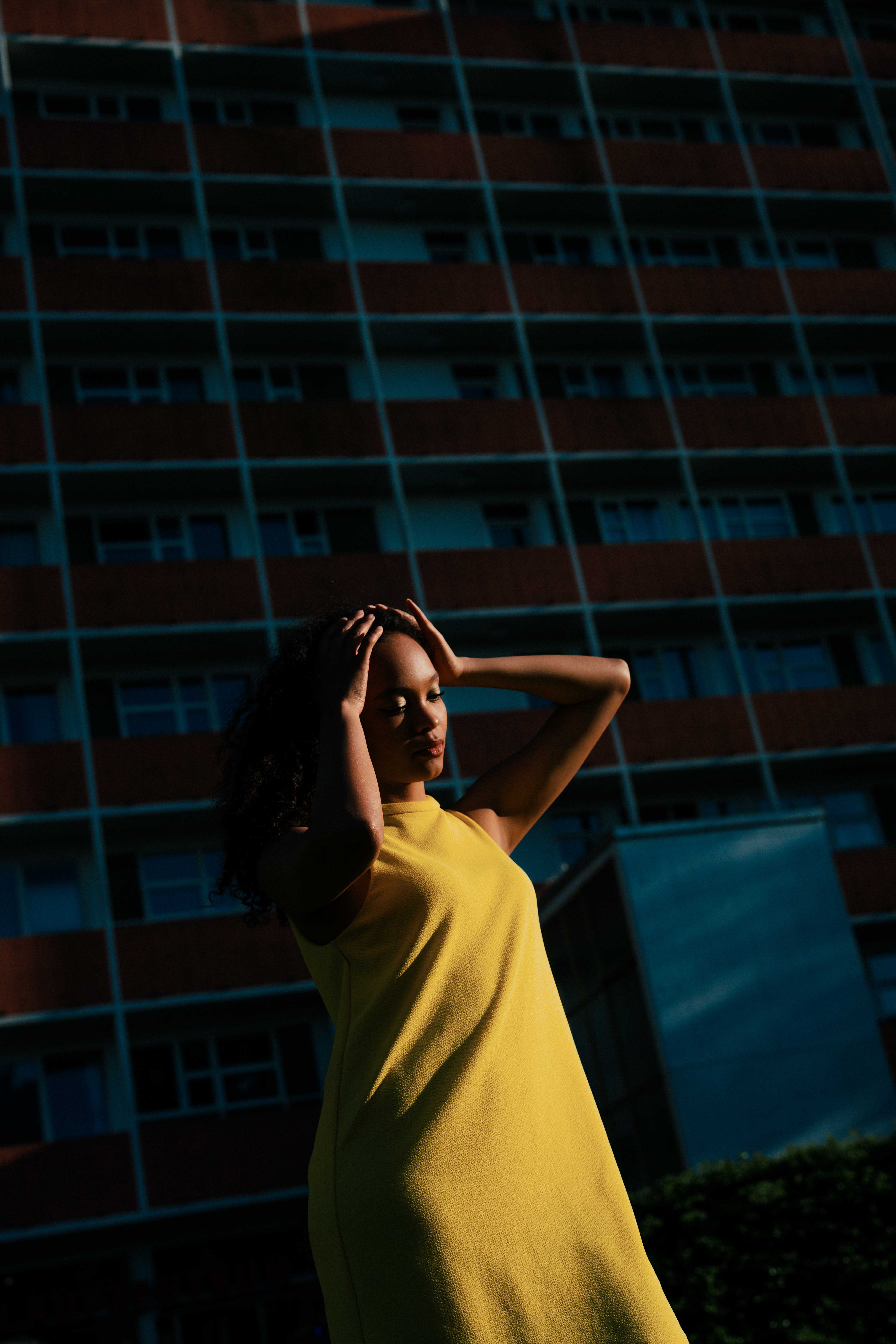 A model in a bright yellow dress standing in front of a modernist building in Berlin’s Hansaviertel at sunset. Shot by Alina Rudya on a Nikon Z6 III.
