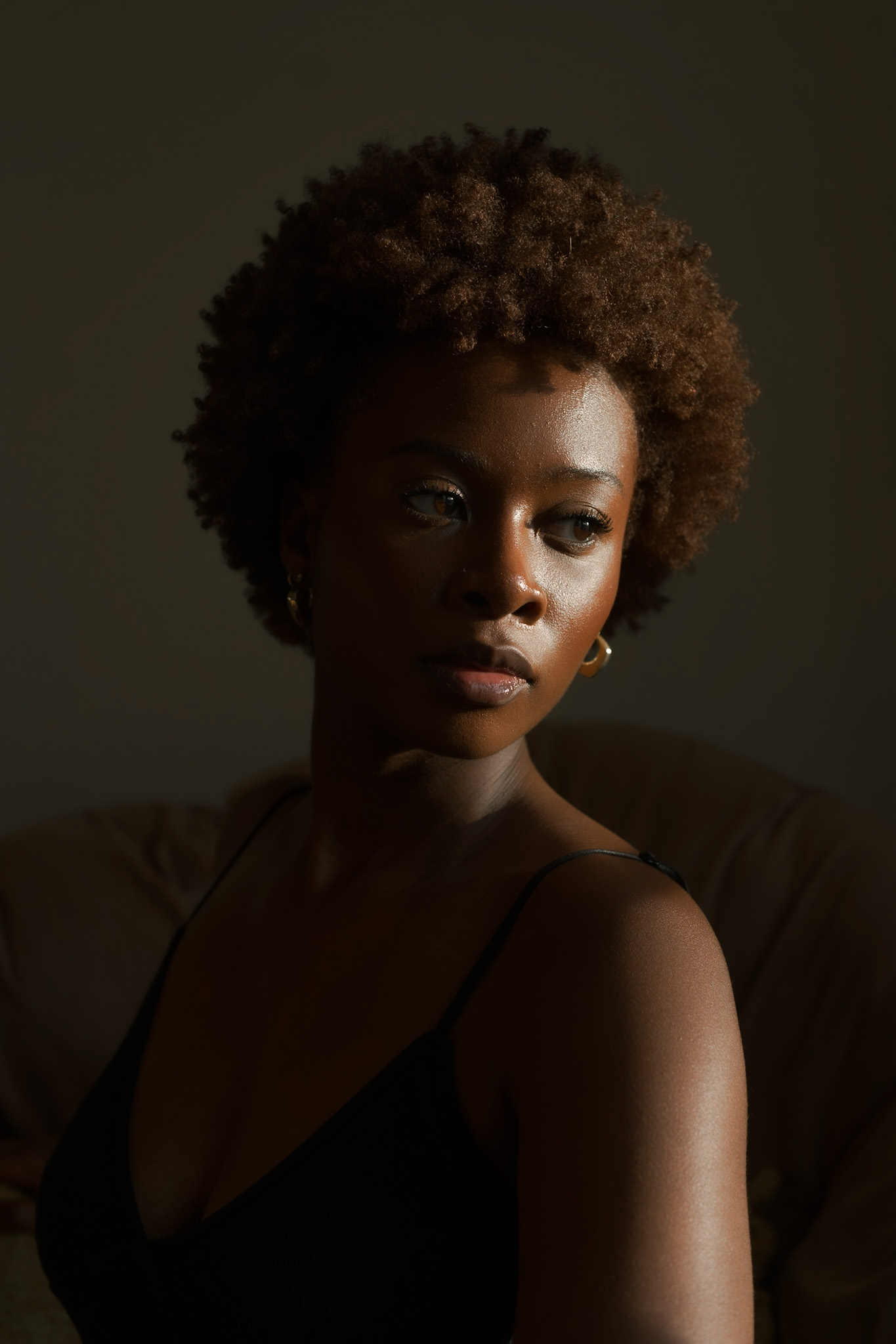 Autoportrait de Damola Akintunde, prise avec une belle lumière et devant un fond foncé.