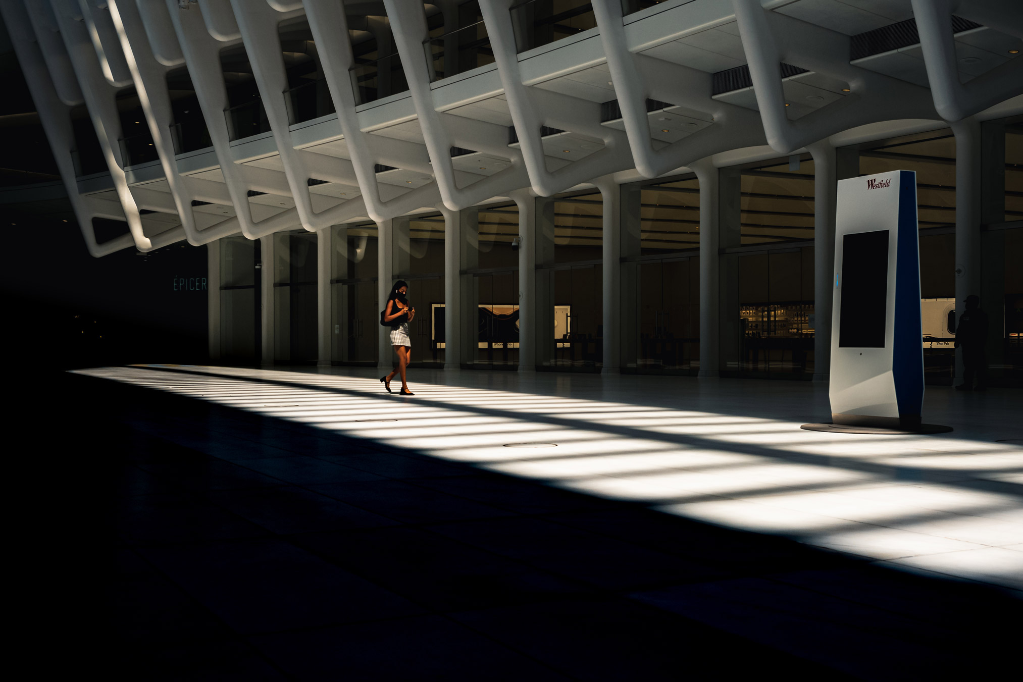 Person walking through light and shadow in the Oculus in New York City, photo by Manuel Pena.