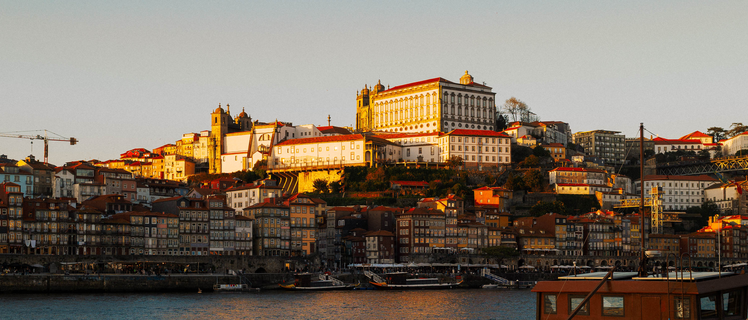 Breite Panoramaaufnahme von Porto im Format 21:9, mit dem berühmten Palácio da Bolsa, der von der Abendsonne angestrahlt wird. Aufgenommen von Connor Redmond mit der Sigma BF.
