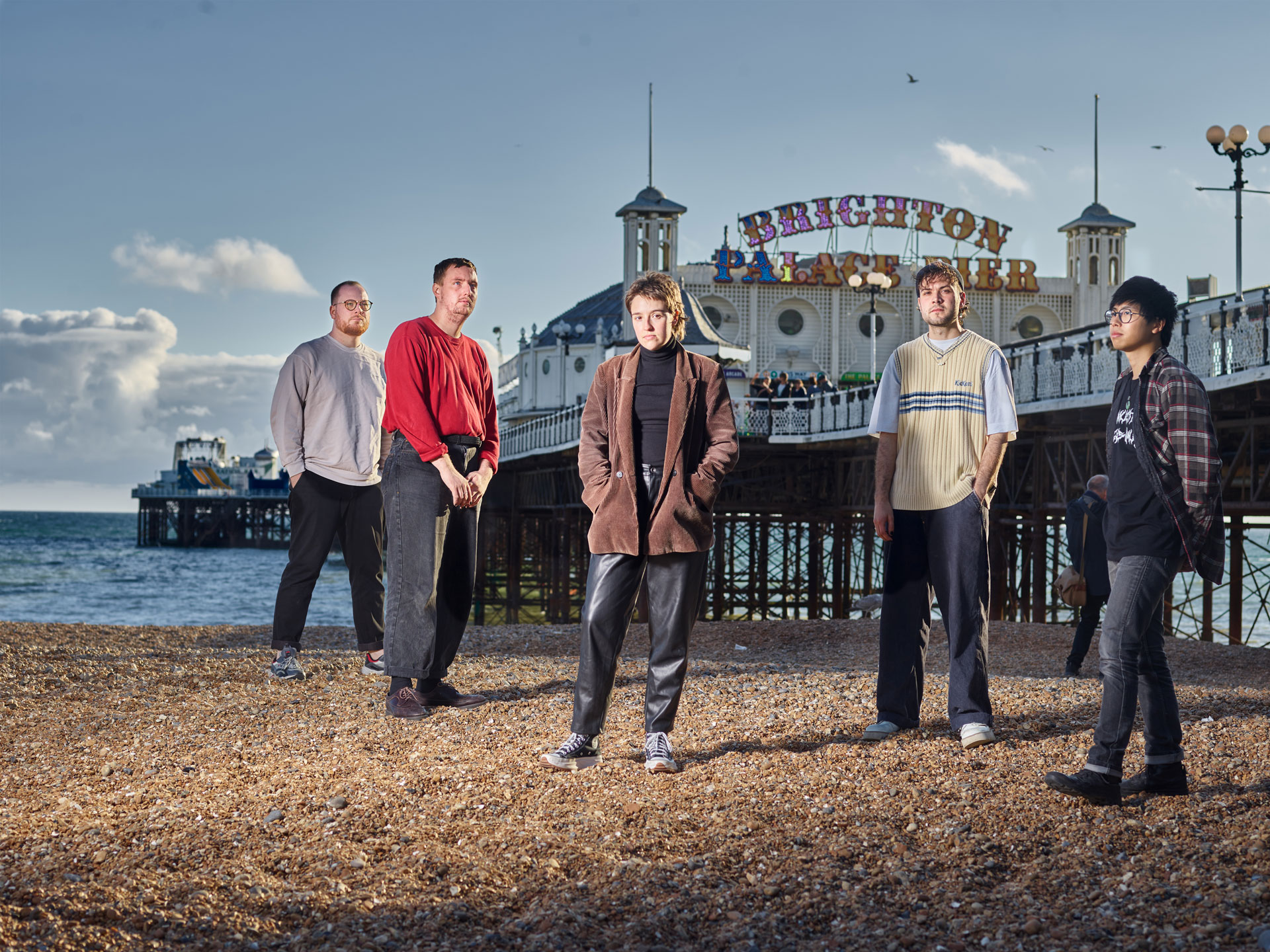 The band ‘Flirting’ on Brighton beach, with the Palace Pier, sea and sky in the background, photo by Ki Price