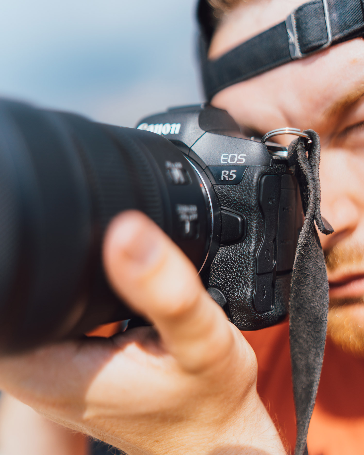Jacob Murray, portant un t-shirt orange et une casquette noir, prend une photo avec son Canon R5 et son objectif RF 24-70 mm f/2.8