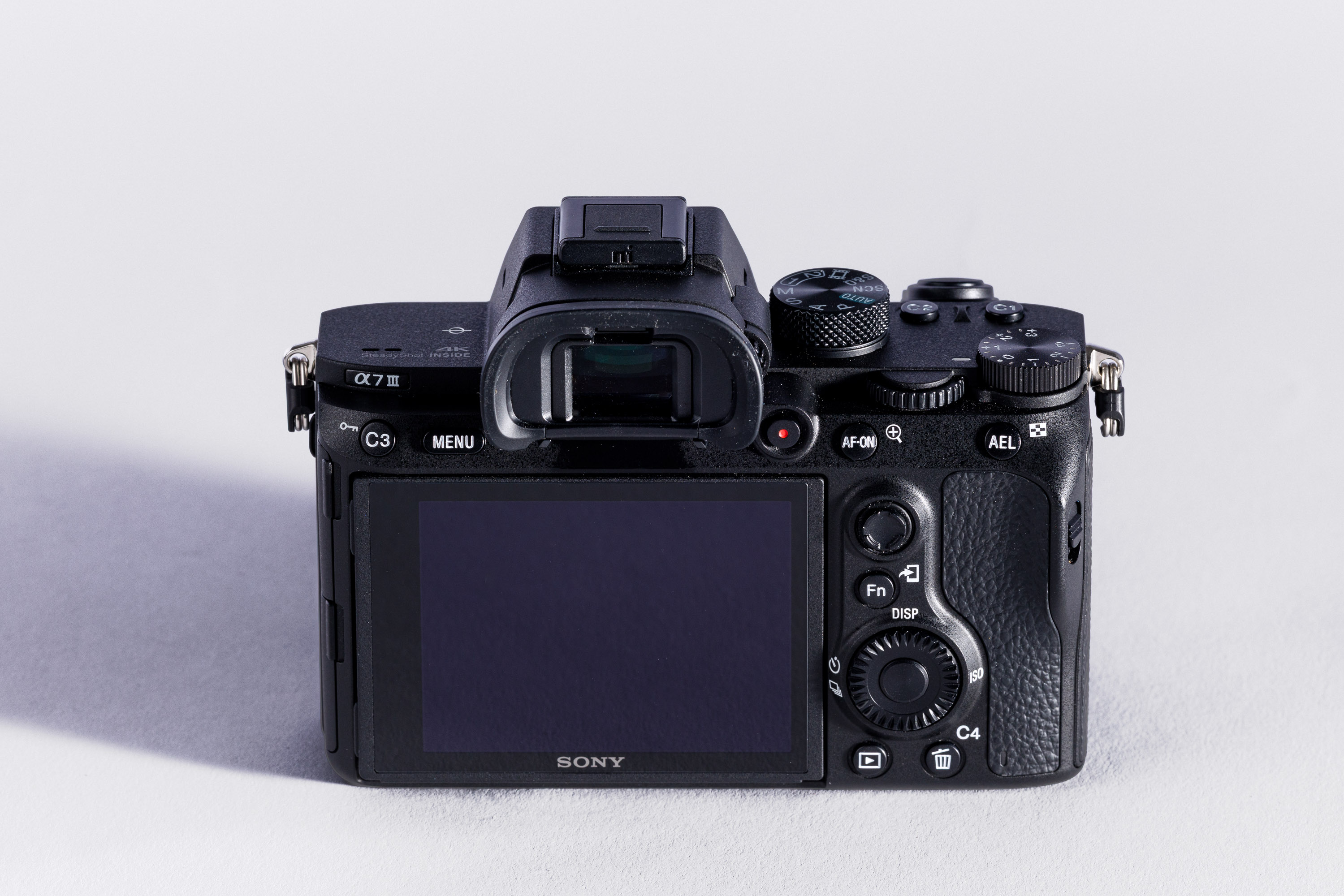 The back of a used Sony A7 III with a close up on viewfinder, screen and dials.