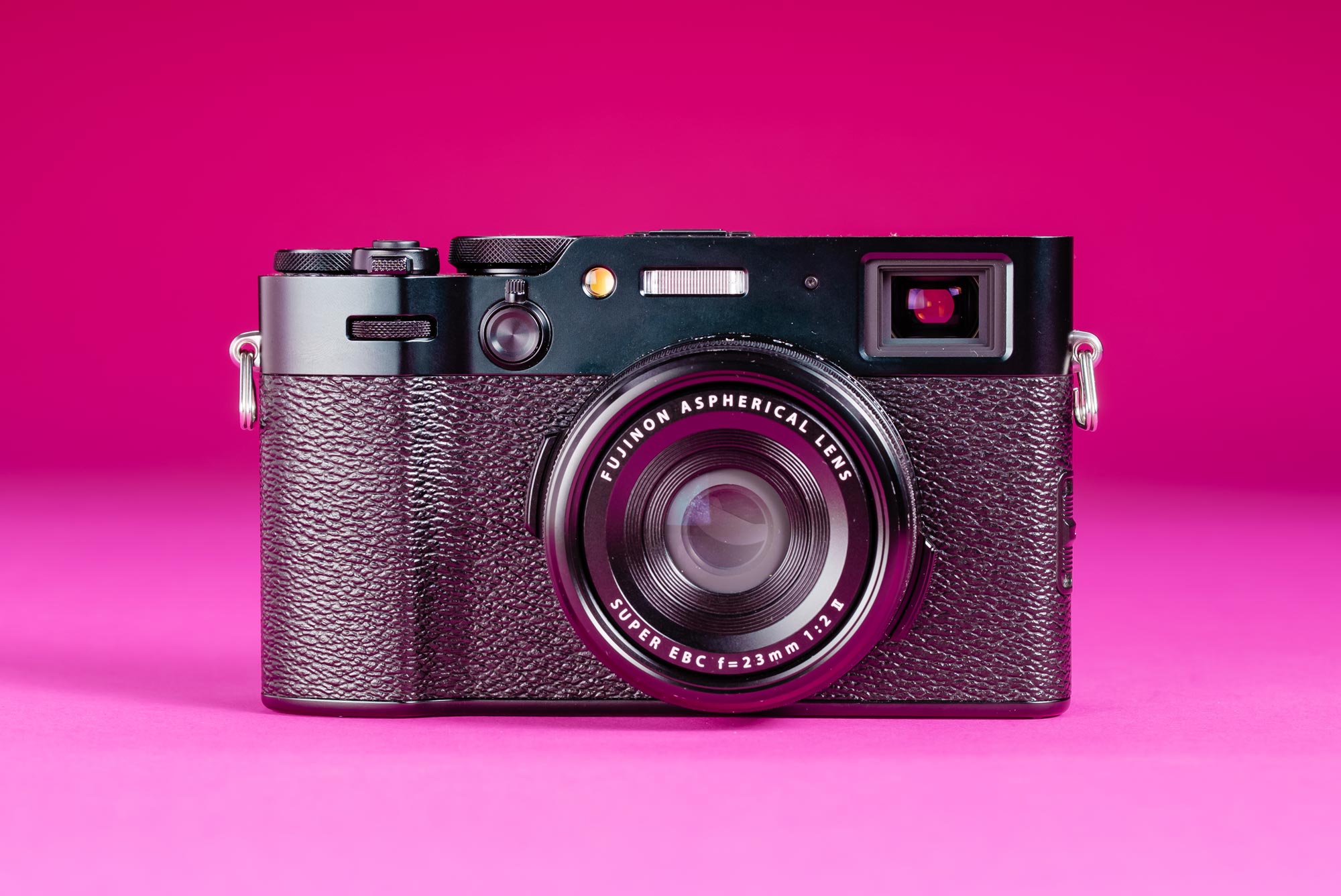 A used Fujifilm X100VI on a graduated pink background.