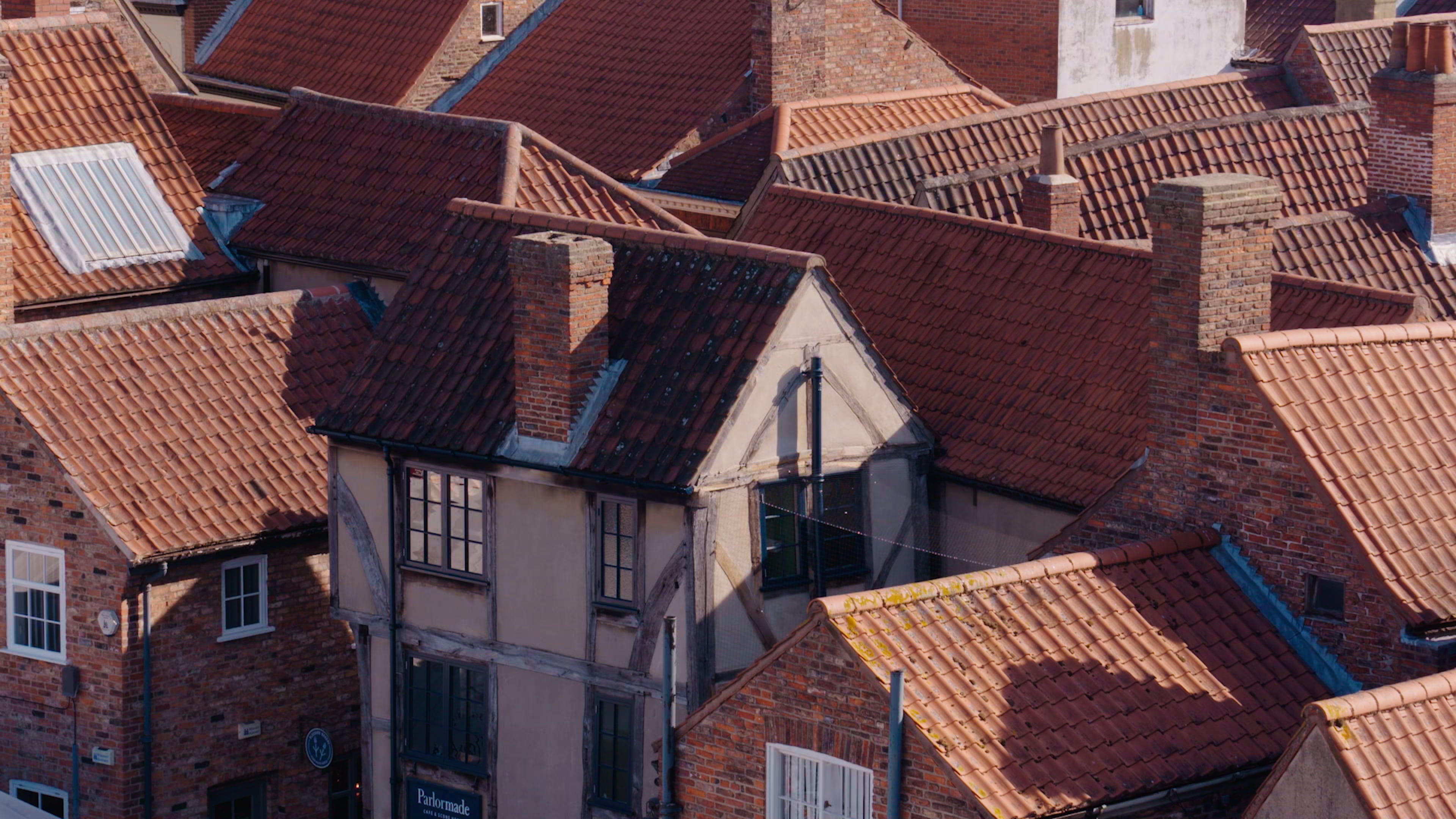 Ein altes Holzhaus im Tudor-Stil, umgeben von roten Backsteinhäusern in York, aufgenommen als Teil einer Eröffnungsszene