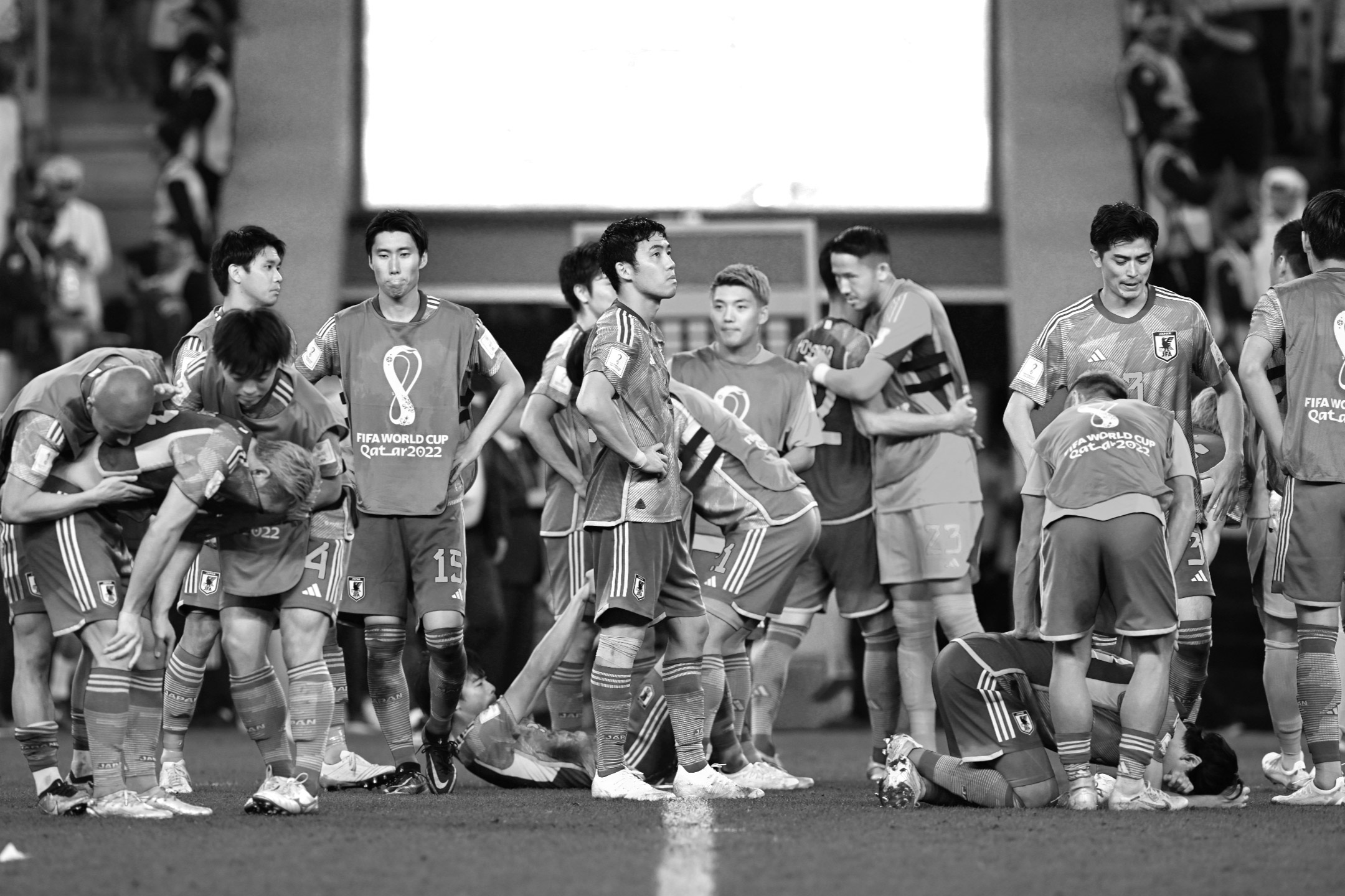 Ein Schwarz-Weiß-Foto der japanischen Mannschaft, die sich nach der Niederlage im Elfmeterschießen gegen Kroatien im Achtelfinale der Fußball-Weltmeisterschaft 2022 gegenseitig tröstet, aufgenommen von Ryu Voelkel mit einer Nikon Z9.