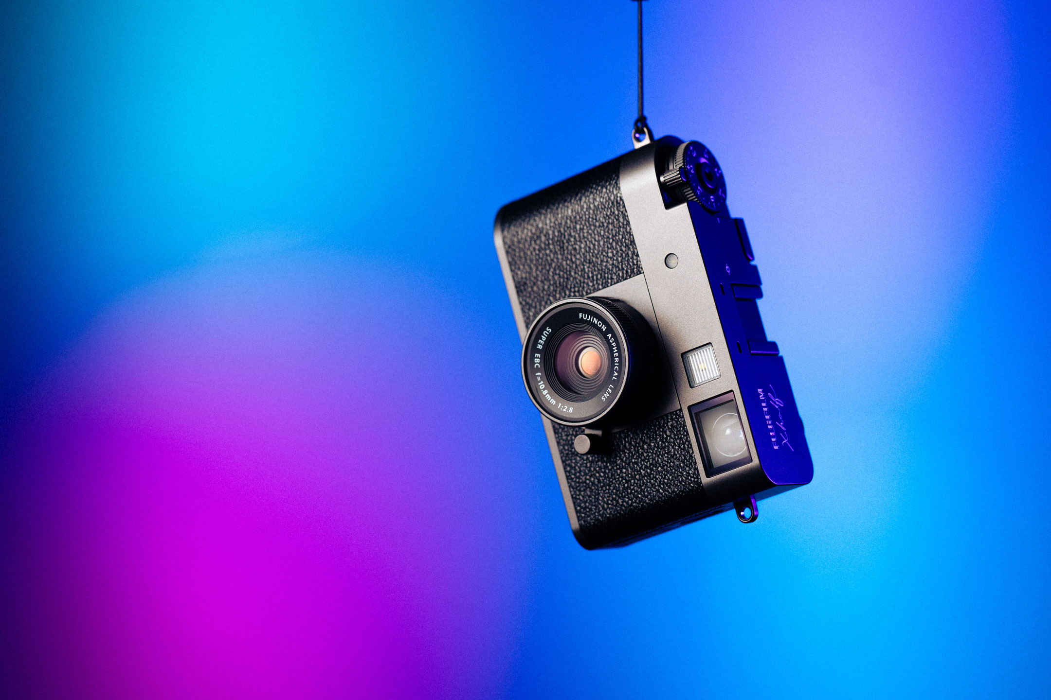 Hängende Fujifilm X half auf blau-pinkem Hintergrund.