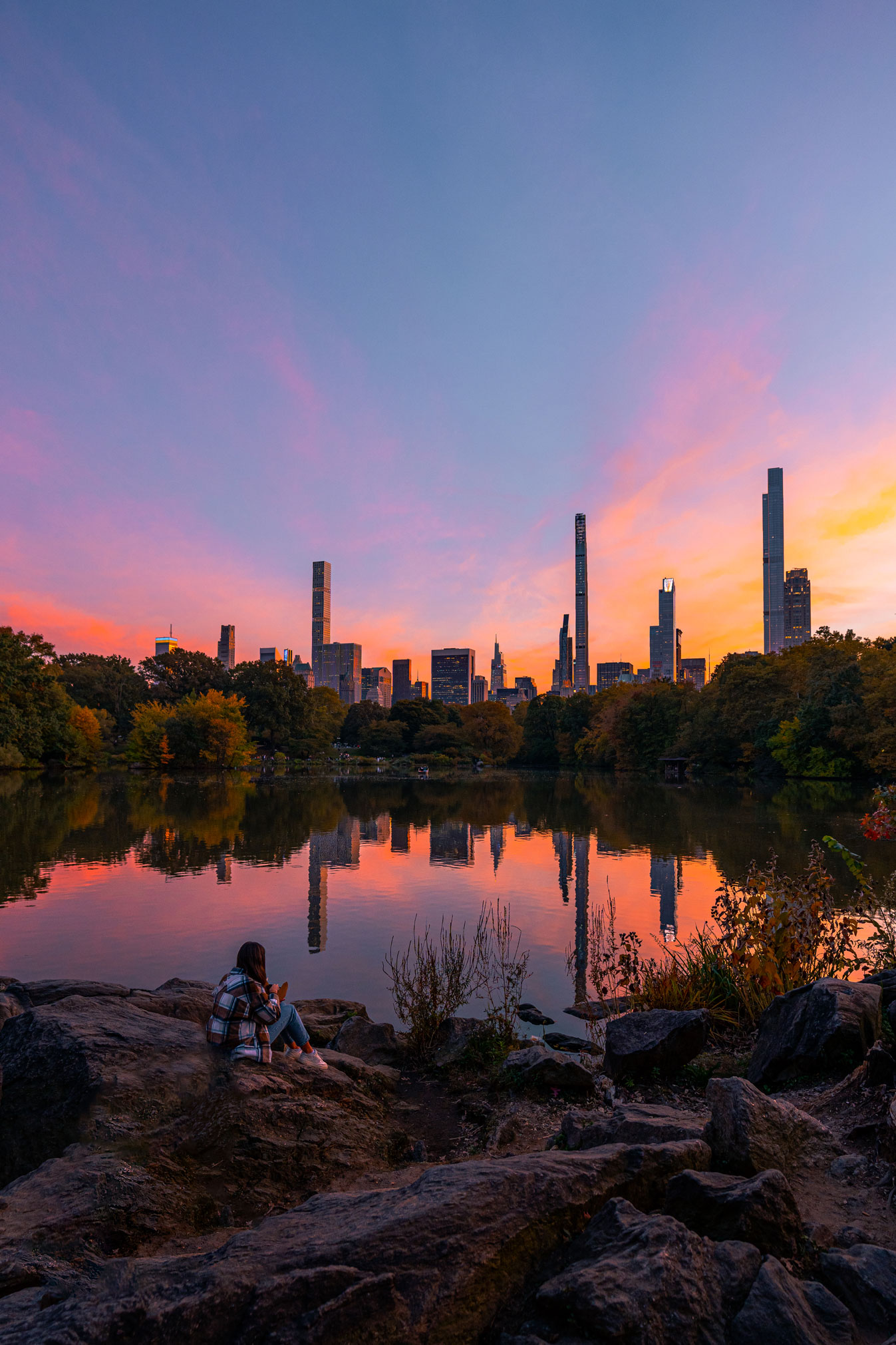 Ein Foto von einer Person, die auf einem Felsen in der Nähe des Wassers im Central Park von New York City sitzt.