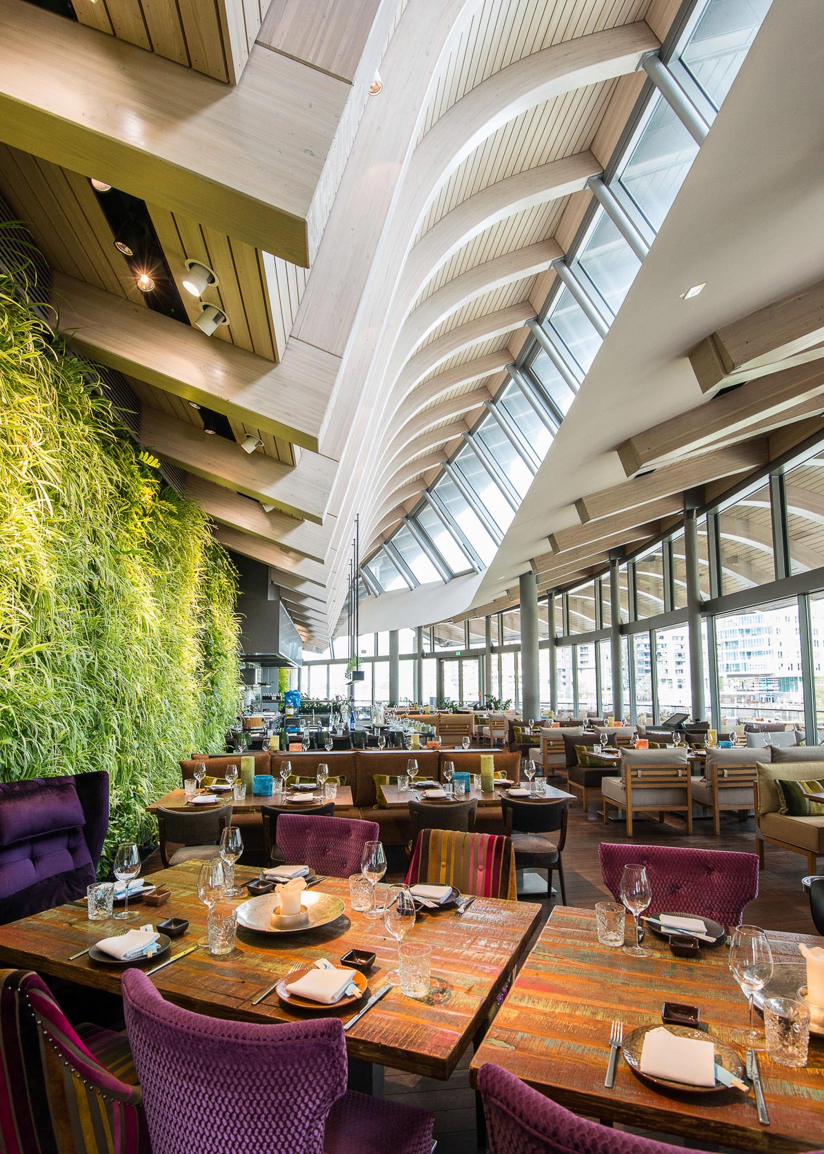 Bild von einem Restaurant mit braunen Tischen und einer Grasswand 

