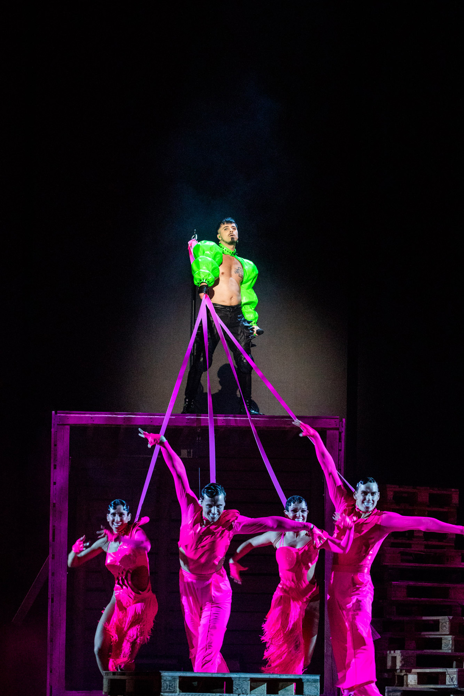 A performer wearing green stands above four dancers wearing pink on stage at Eurovision 2023, shot by Chloe Hashemi with the Canon EOS 5D Mark IV.

