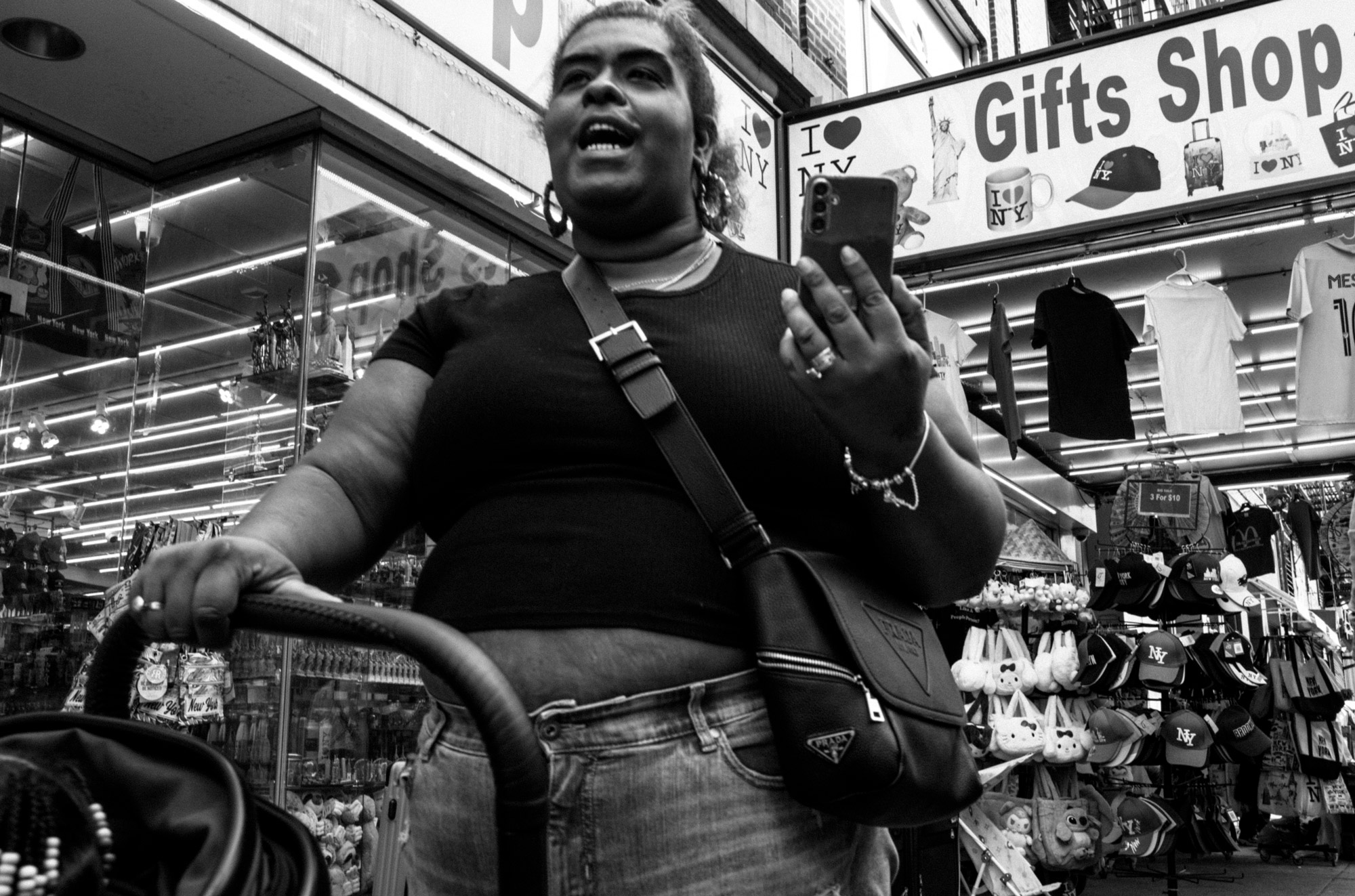A black-and-white photo of a person holding a phone and pushing a stroller