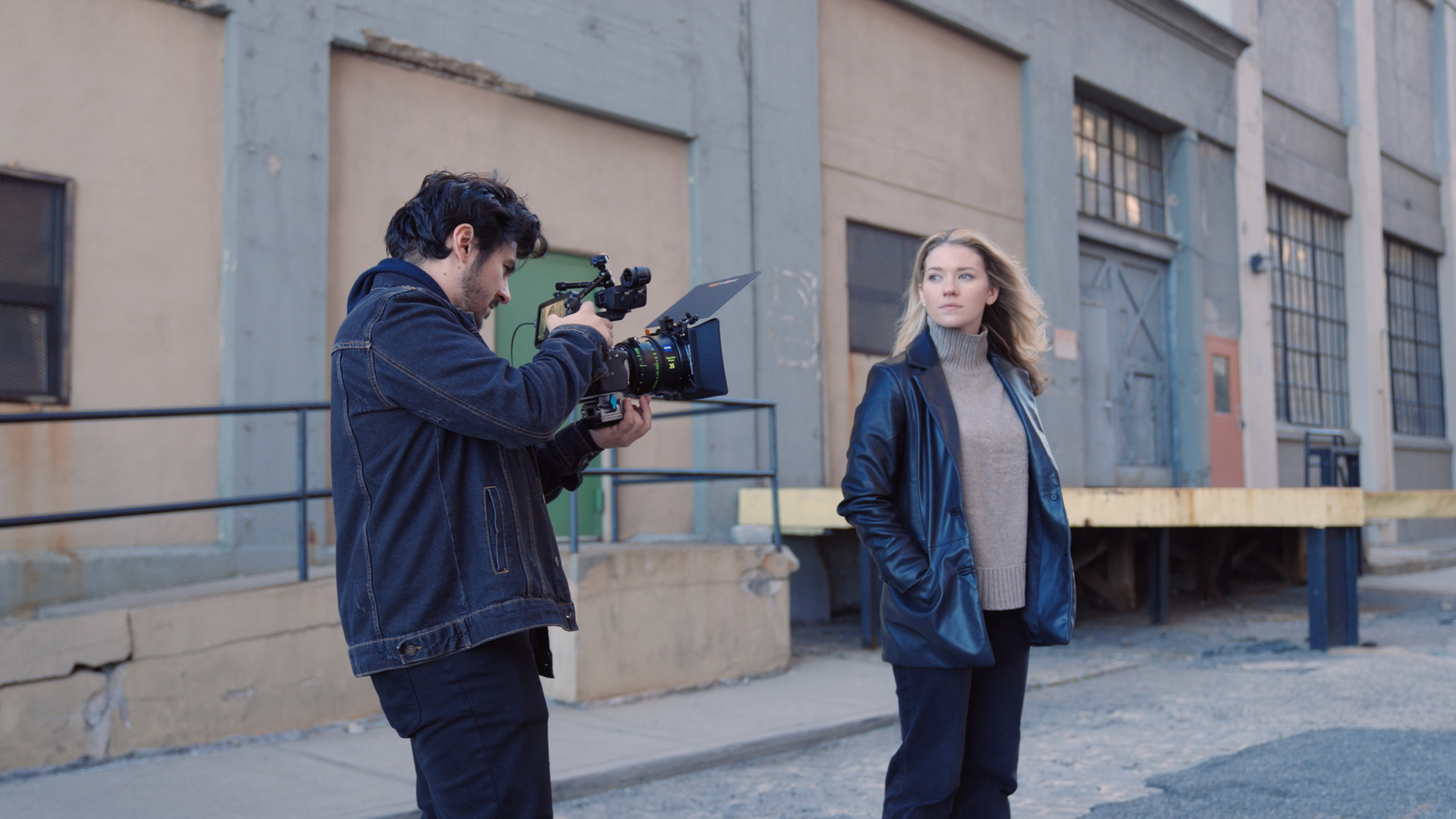 Videographer hand holding Sony Fx3 shooting model in front of grey and brown buildings