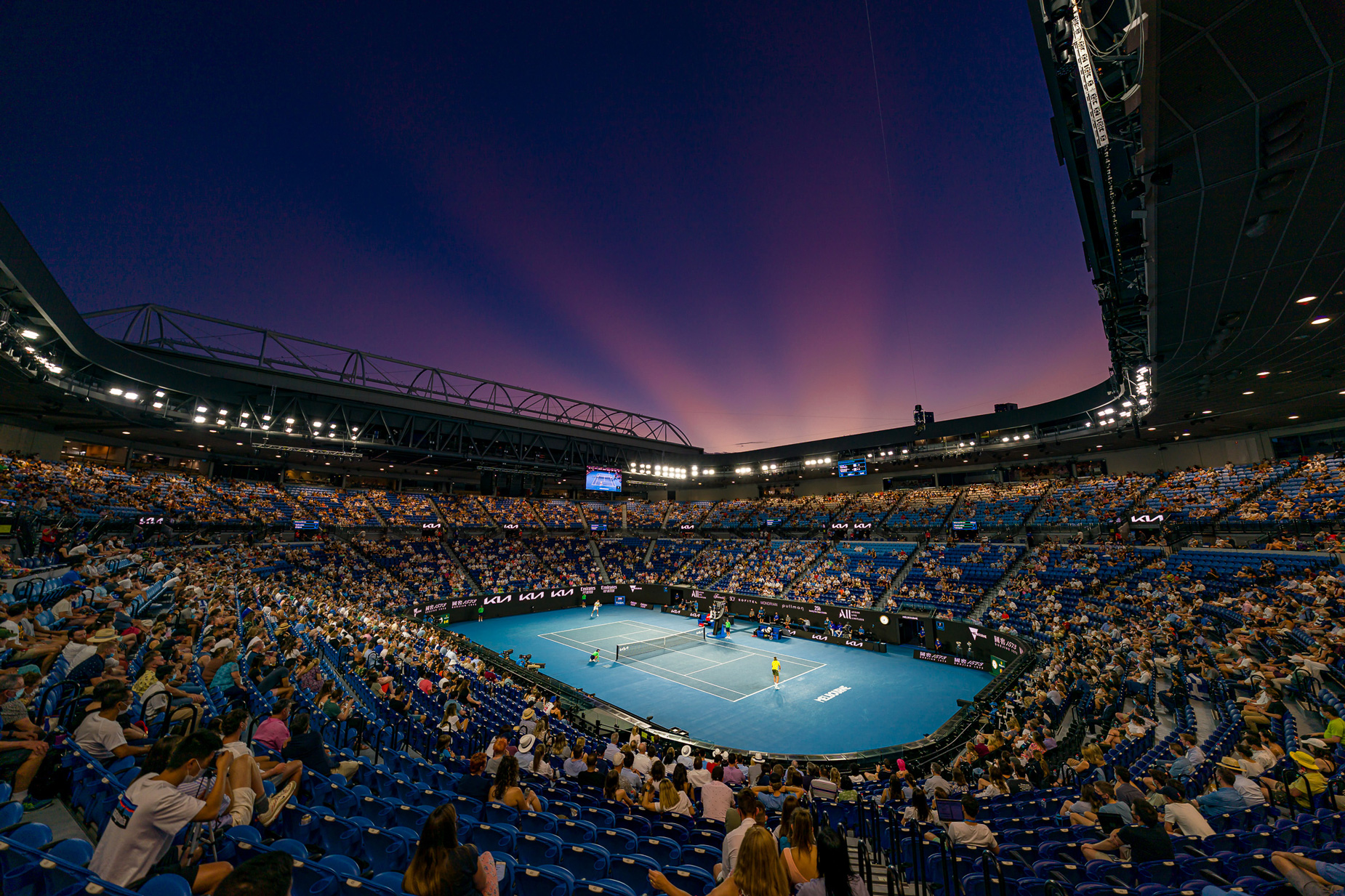 Evening tennis match with a purple sunset.