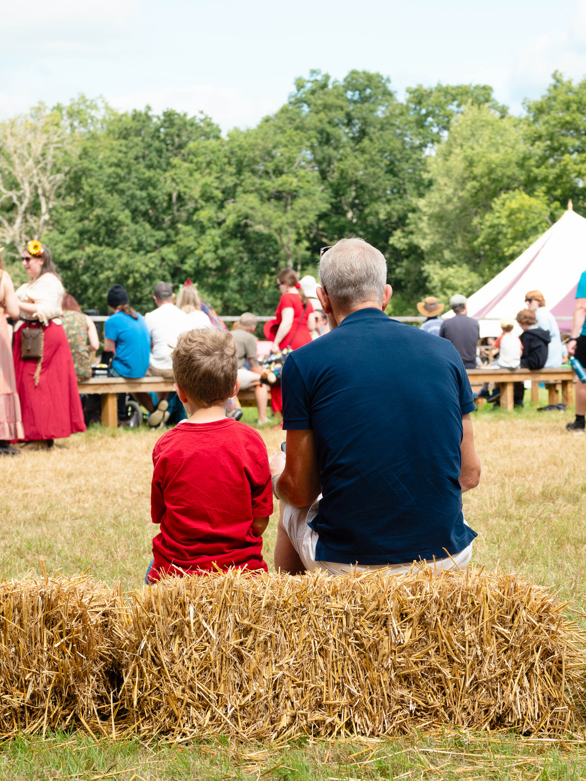 Two people sitting on a bench at a festival, by Jakub Golis with an OM System OM-3