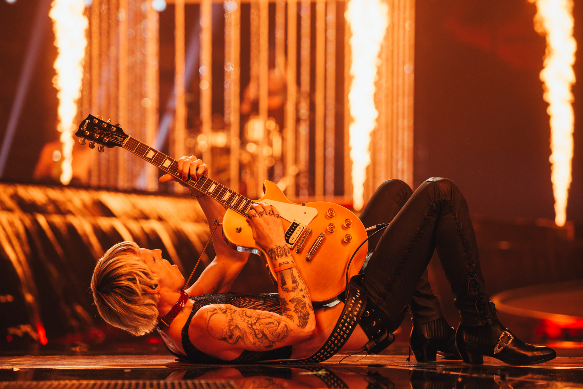 A musician lies on their back while playing the guitar on stage at Eurovision.