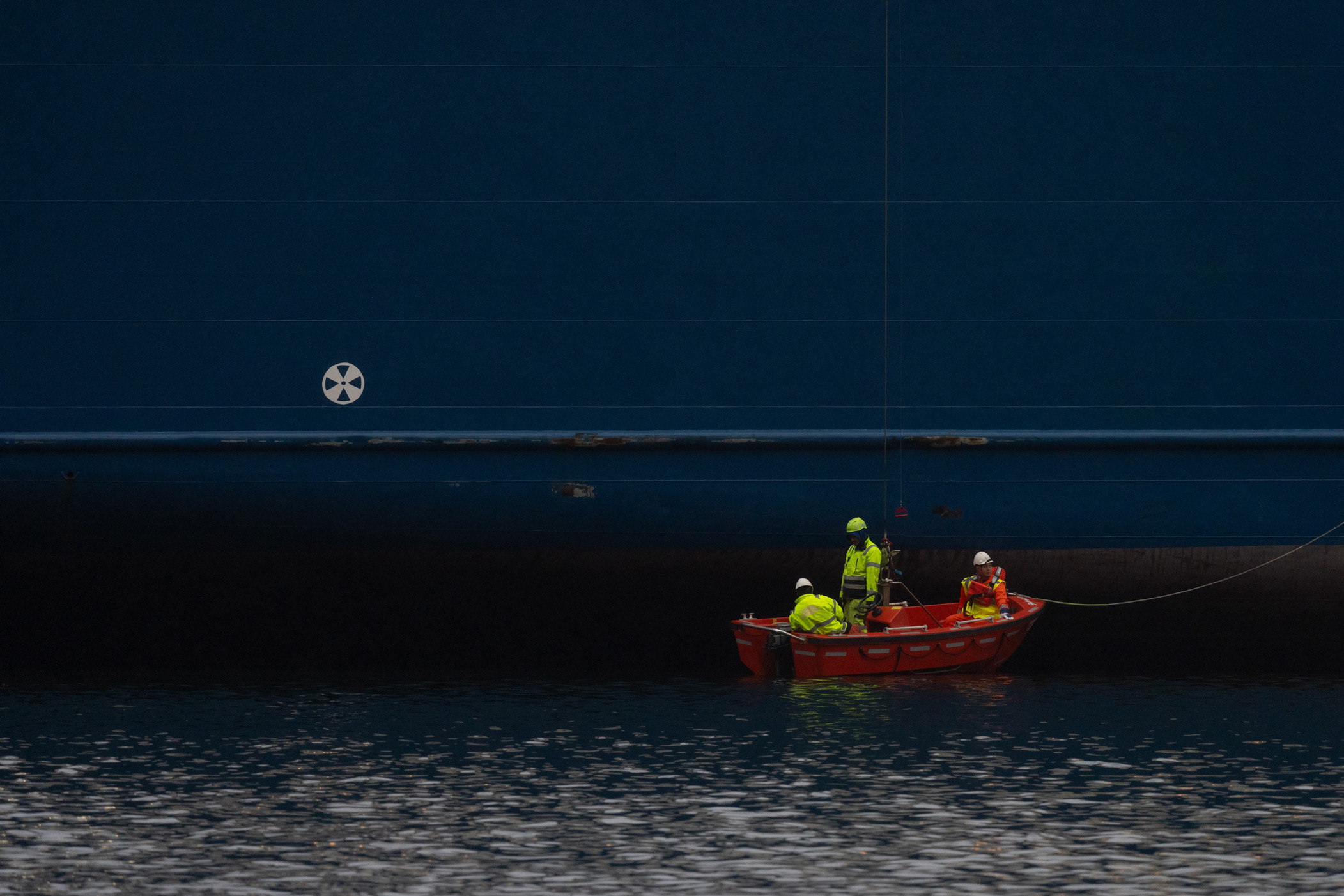 Shot of people in a red boat next to a large ship in Norway