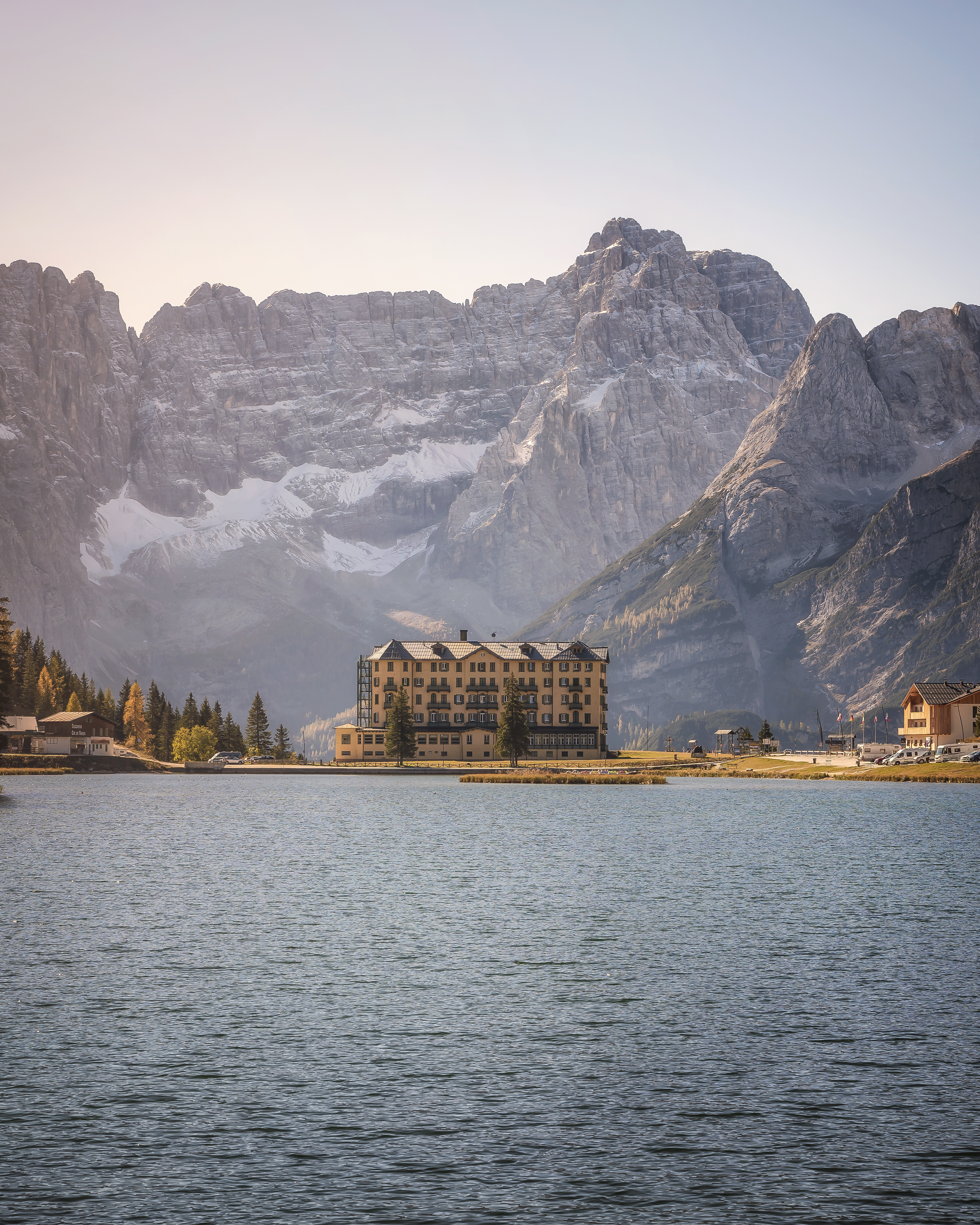 Vista sul Lago di Misurina con un grande hotel color ocra sulla riva e le Dolomiti sullo sfondo.