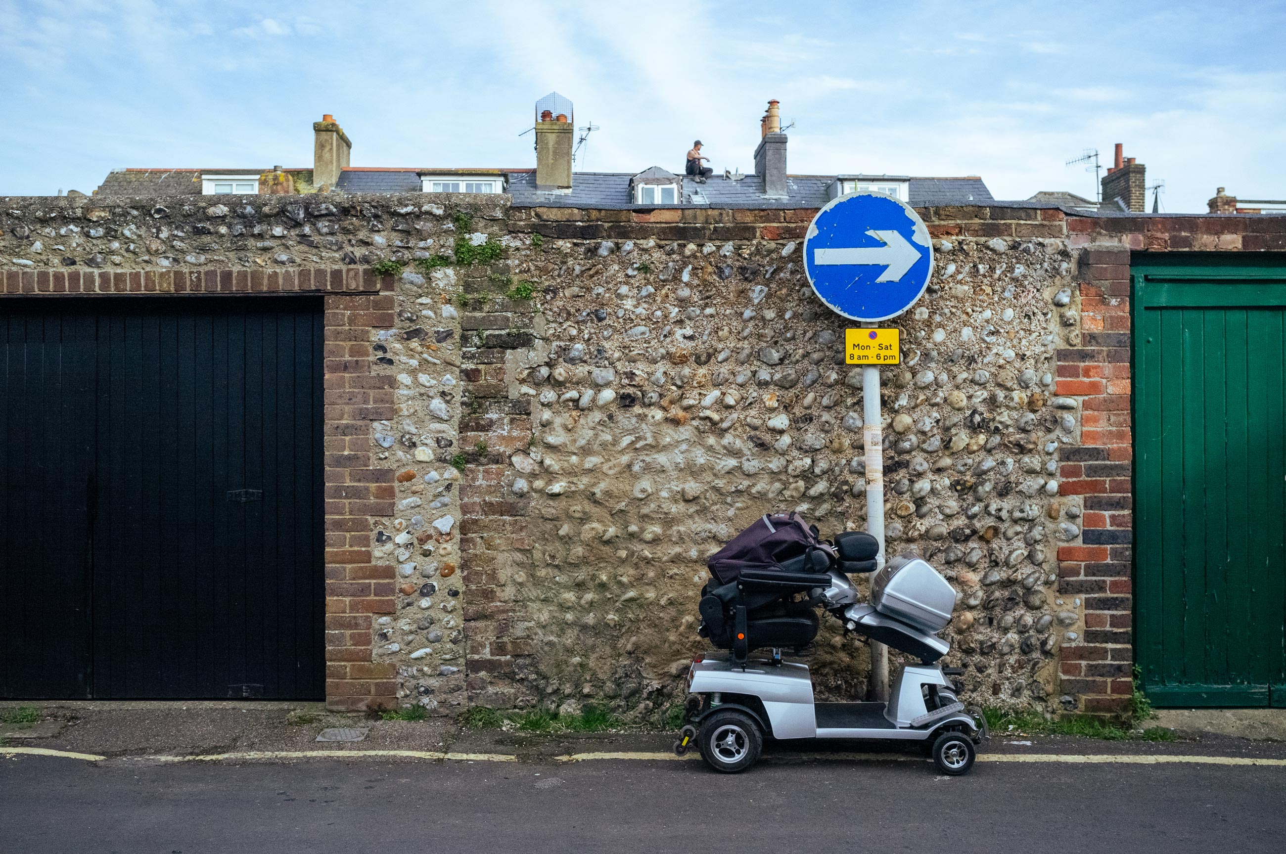 A mobility scooter in front of a road sign on a single yellow line on a road, photo by Jakub Golis with Fujifilm X100