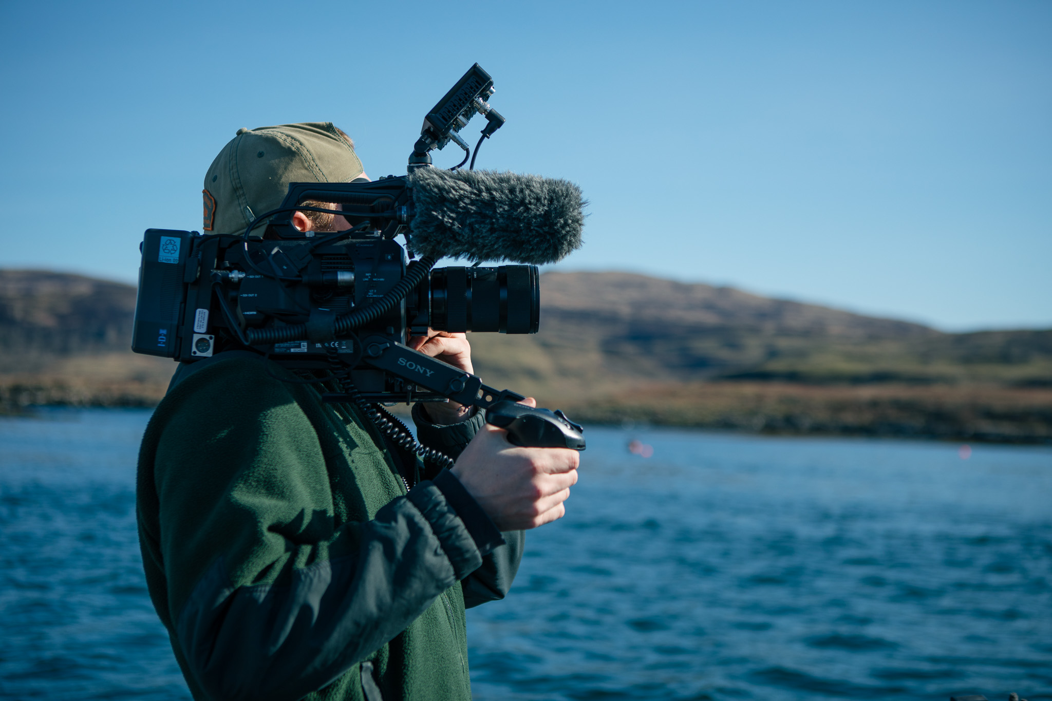 A person with a camera capturing the scenic view of a calm body of water.


