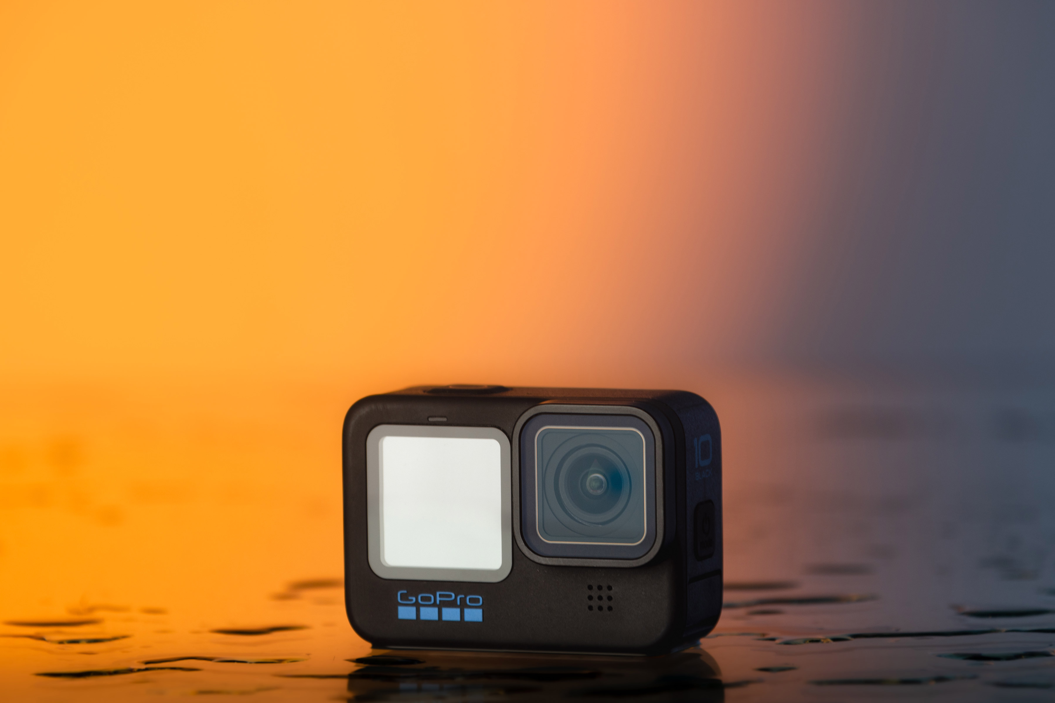 The GoPro Hero 10 on an orange background.