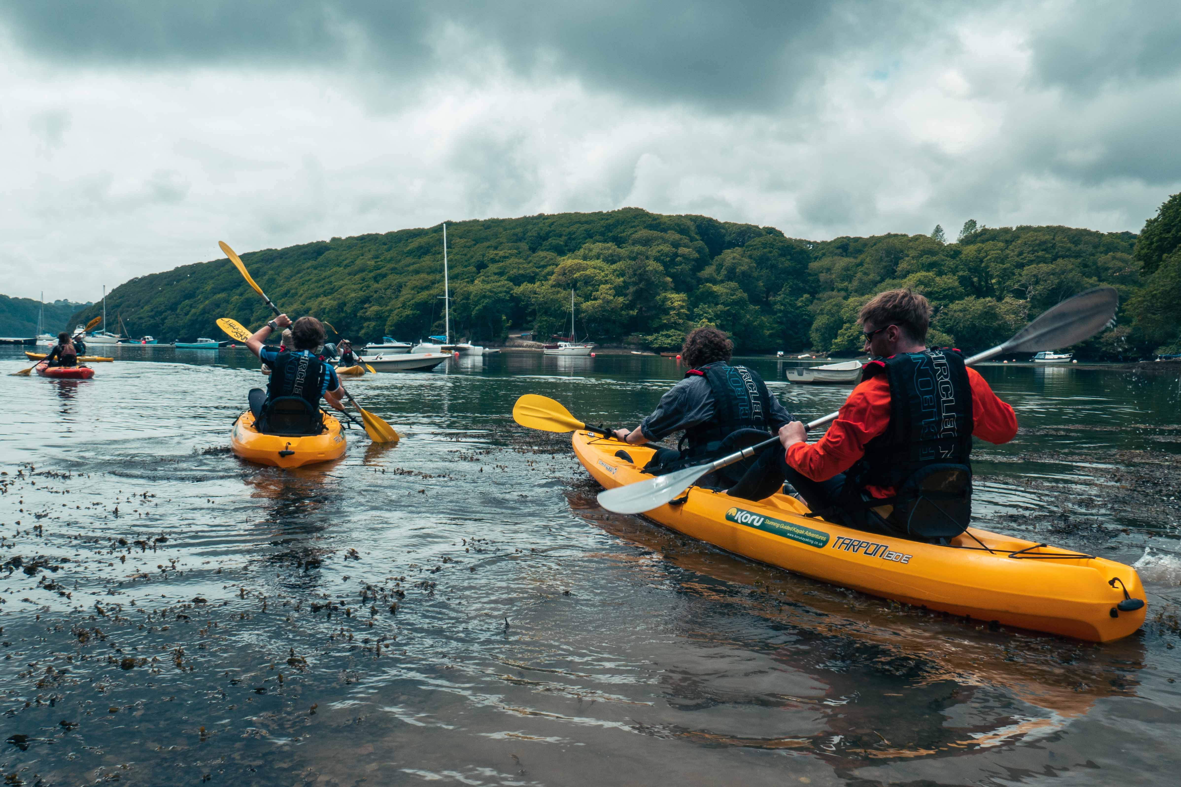 Three kayaks each with two people in them set off in the water 

