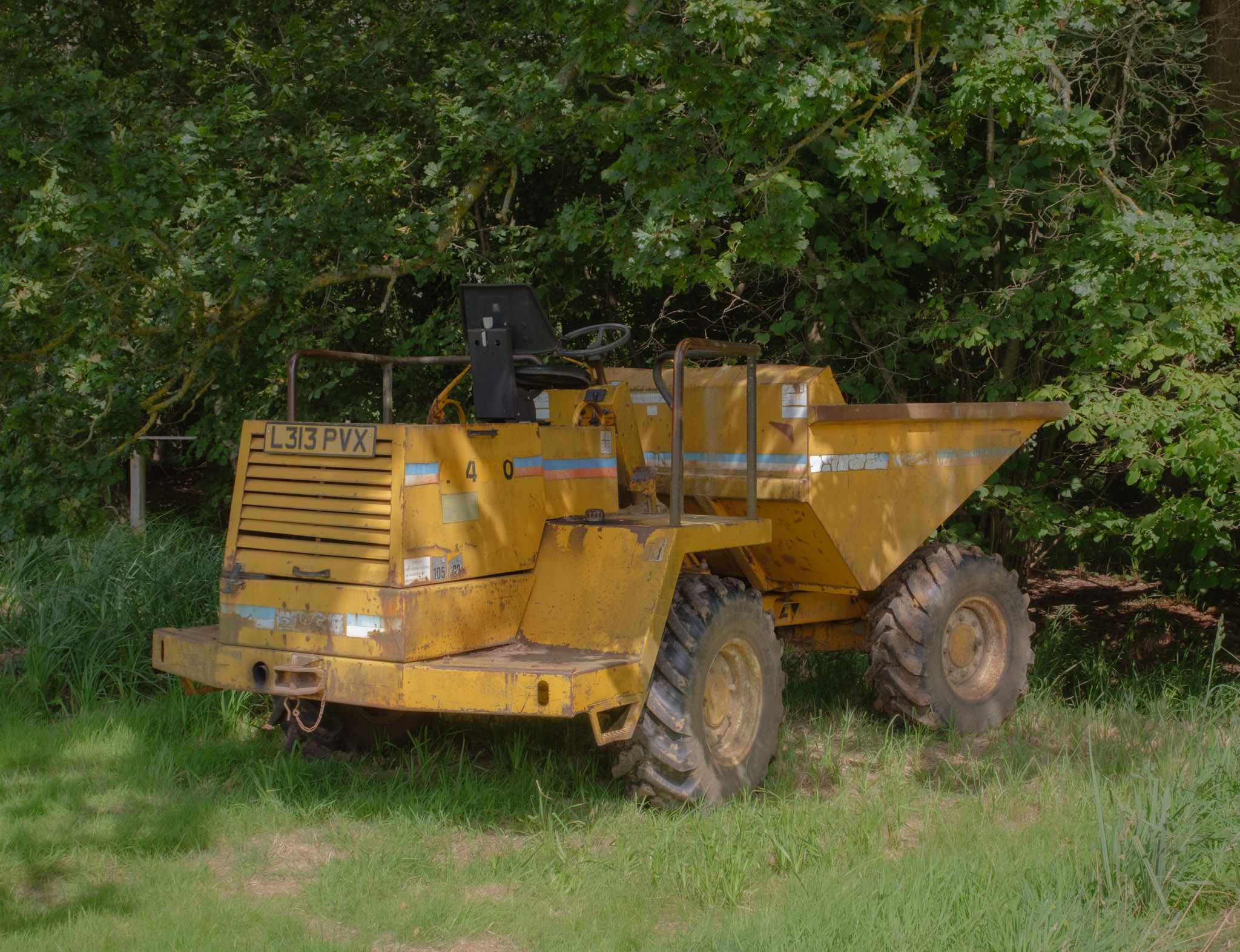 A yellow dump truck parked in a field. By Connor Redmond.