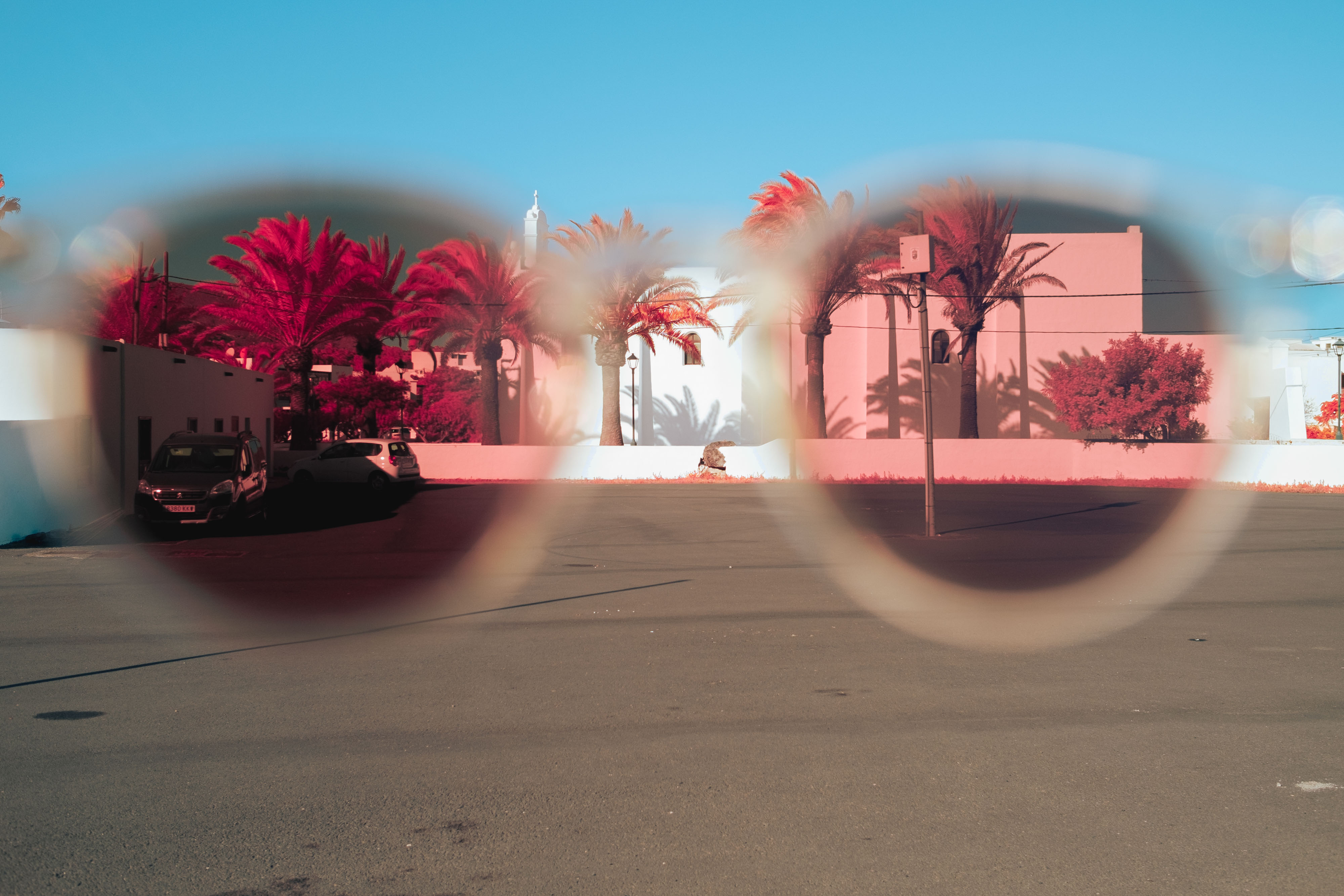 An infrared photo of a street, trees and white houses taken through polarised sunglasses in Lanzarote, shot by Ian Howorth with an IR-Converted Fujifilm X-T1
