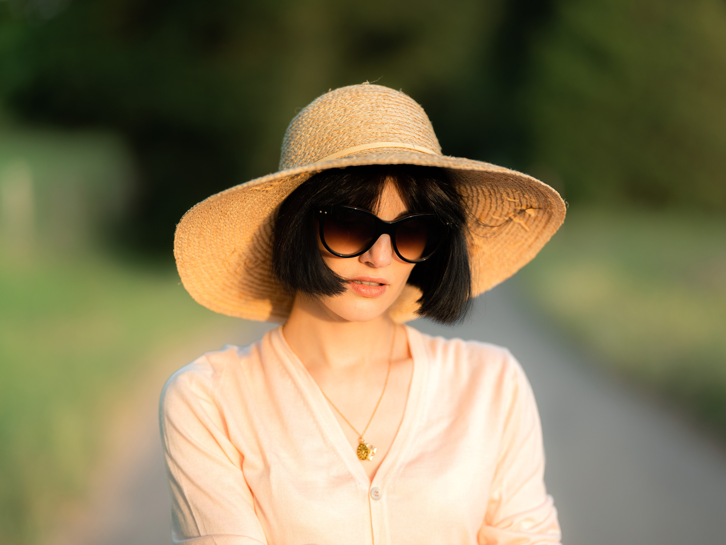 Portrait of a person wearing a sun hat outdoors in a light pink shirt.